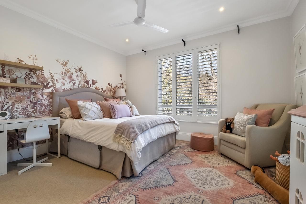 A bedroom with a bed , couch , desk and ceiling fan.