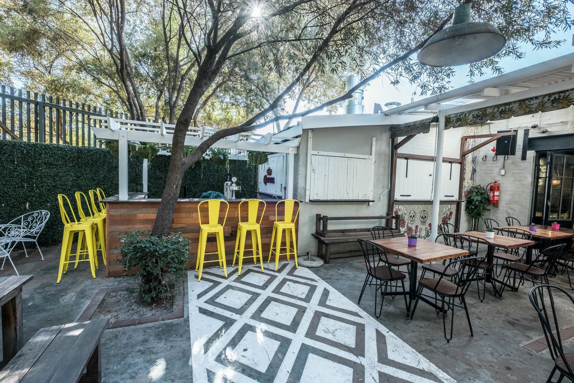 A patio with tables and chairs under a tree.