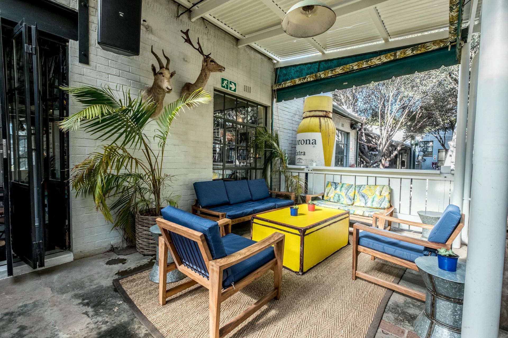 A patio with a couch , chairs , and a yellow coffee table.