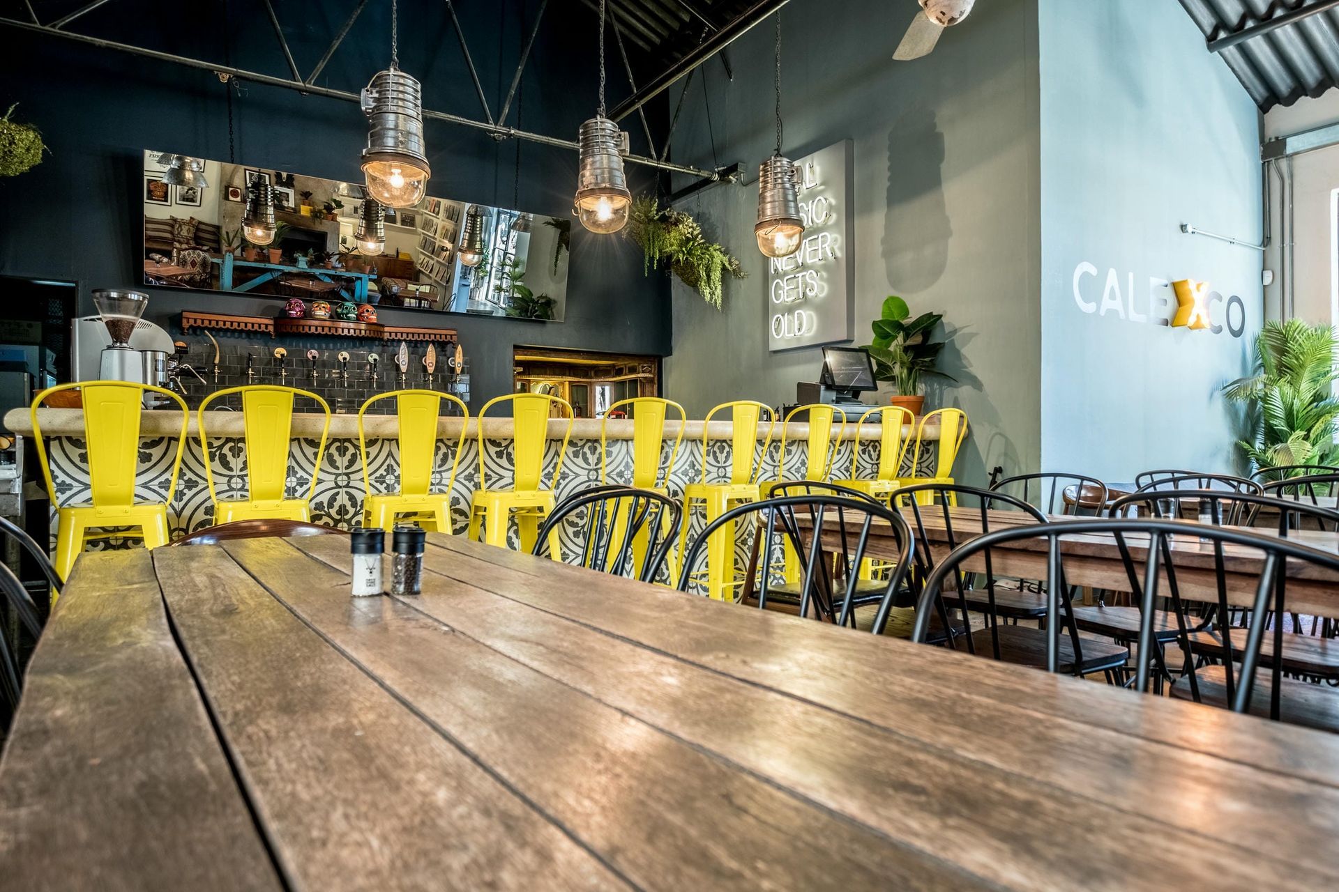 A restaurant with wooden tables and yellow chairs.