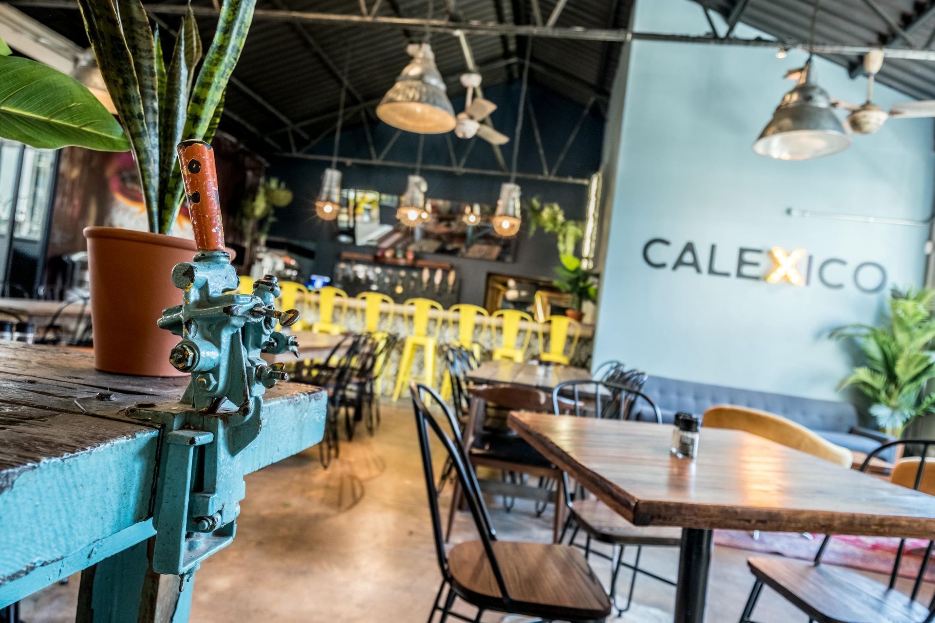 A restaurant with tables and chairs and a sign that says calexico