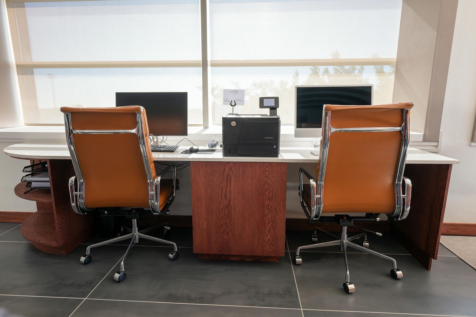 Two chairs are sitting at a desk in front of two computer monitors.