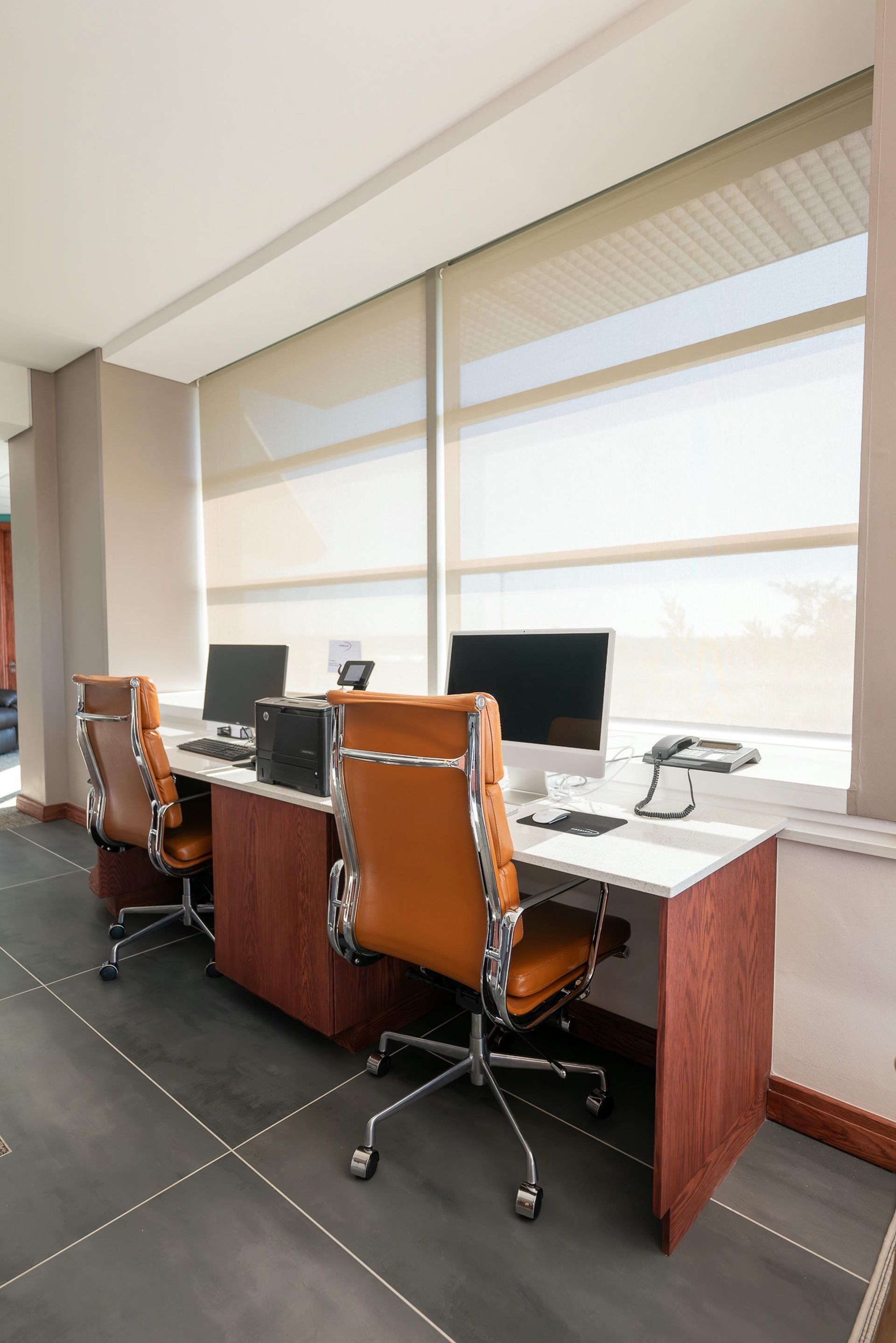 A room with two desks and chairs with computers on them