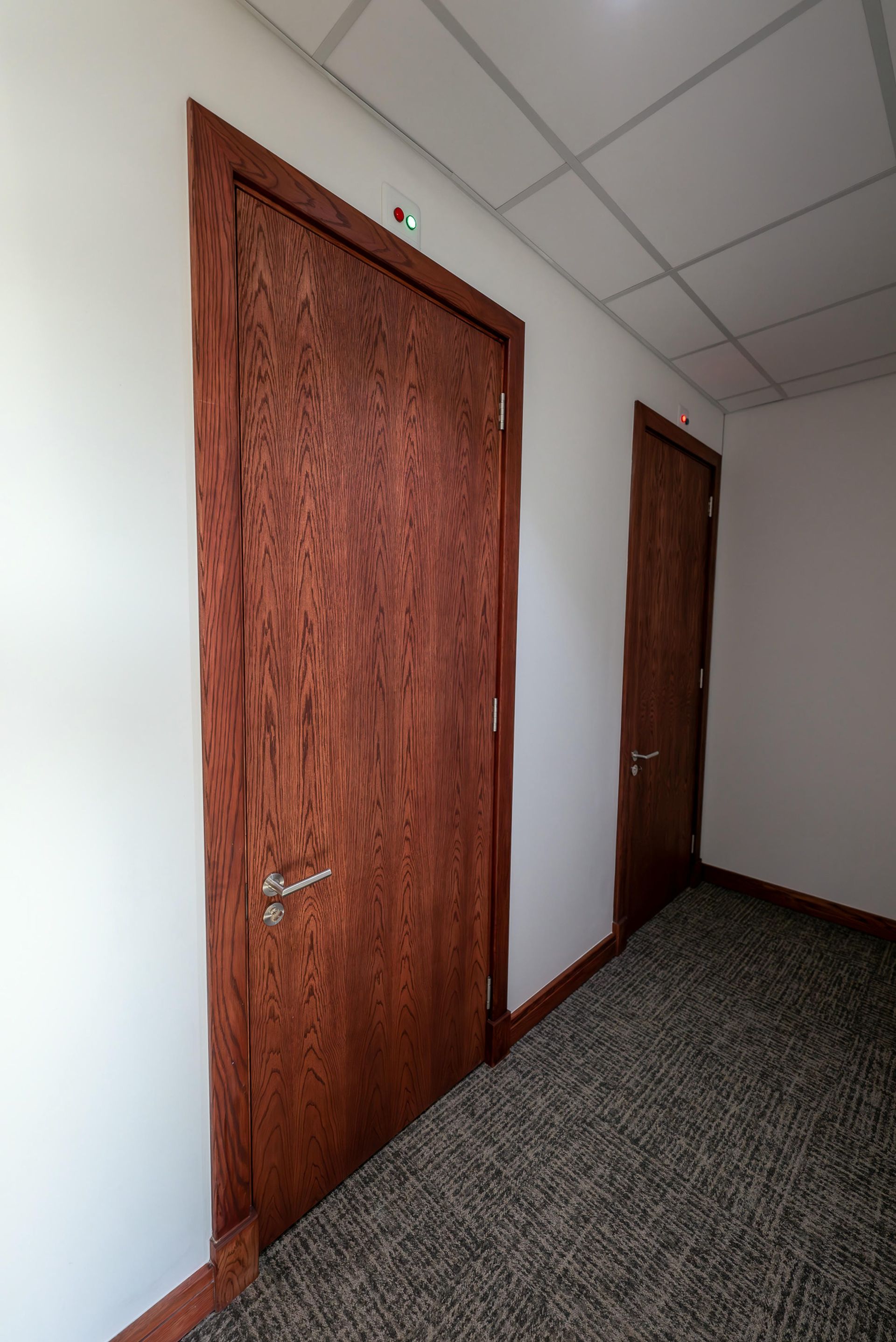 A hallway with two wooden doors and a carpeted floor