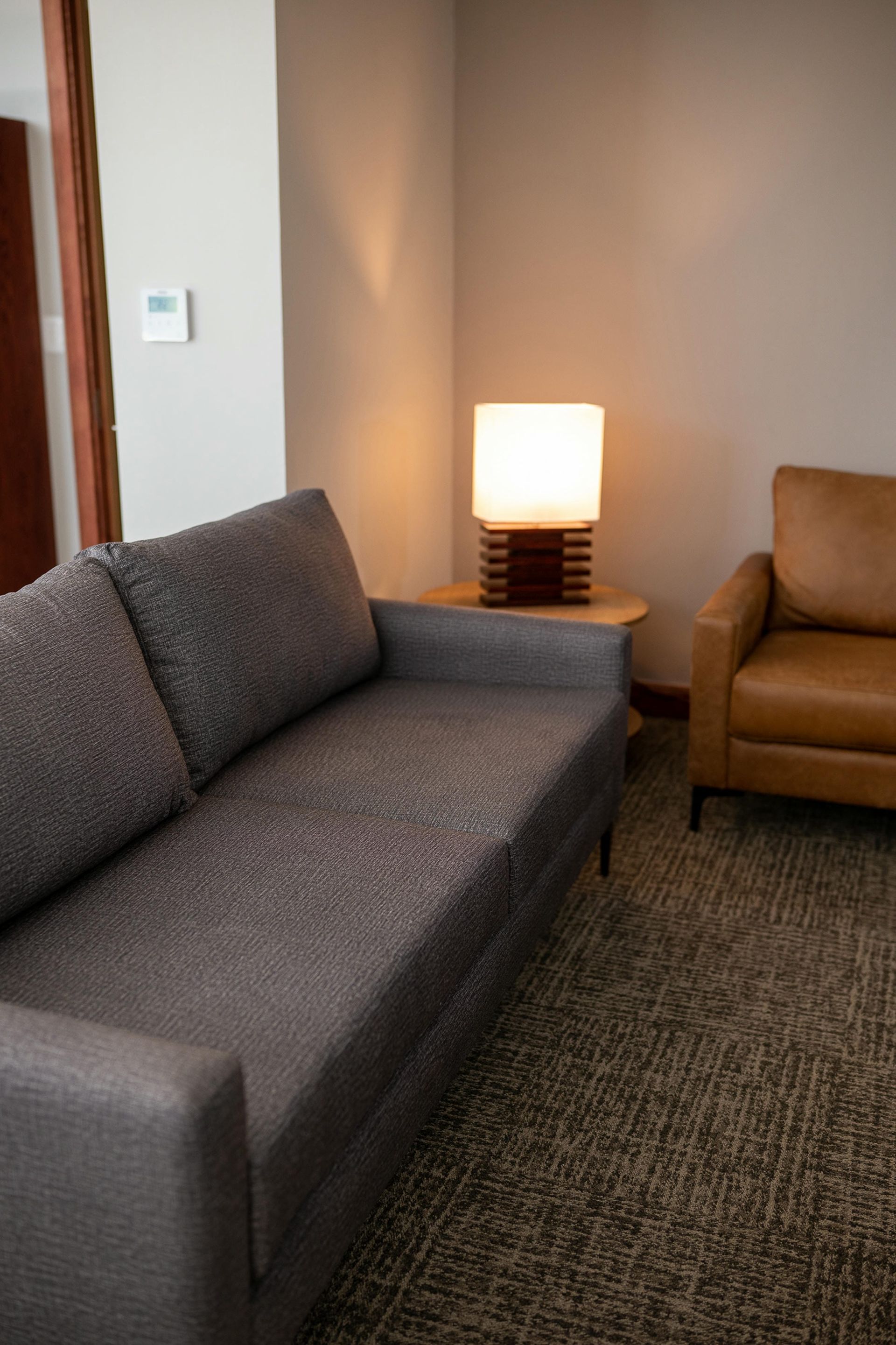 A living room with a couch , chair and lamp.