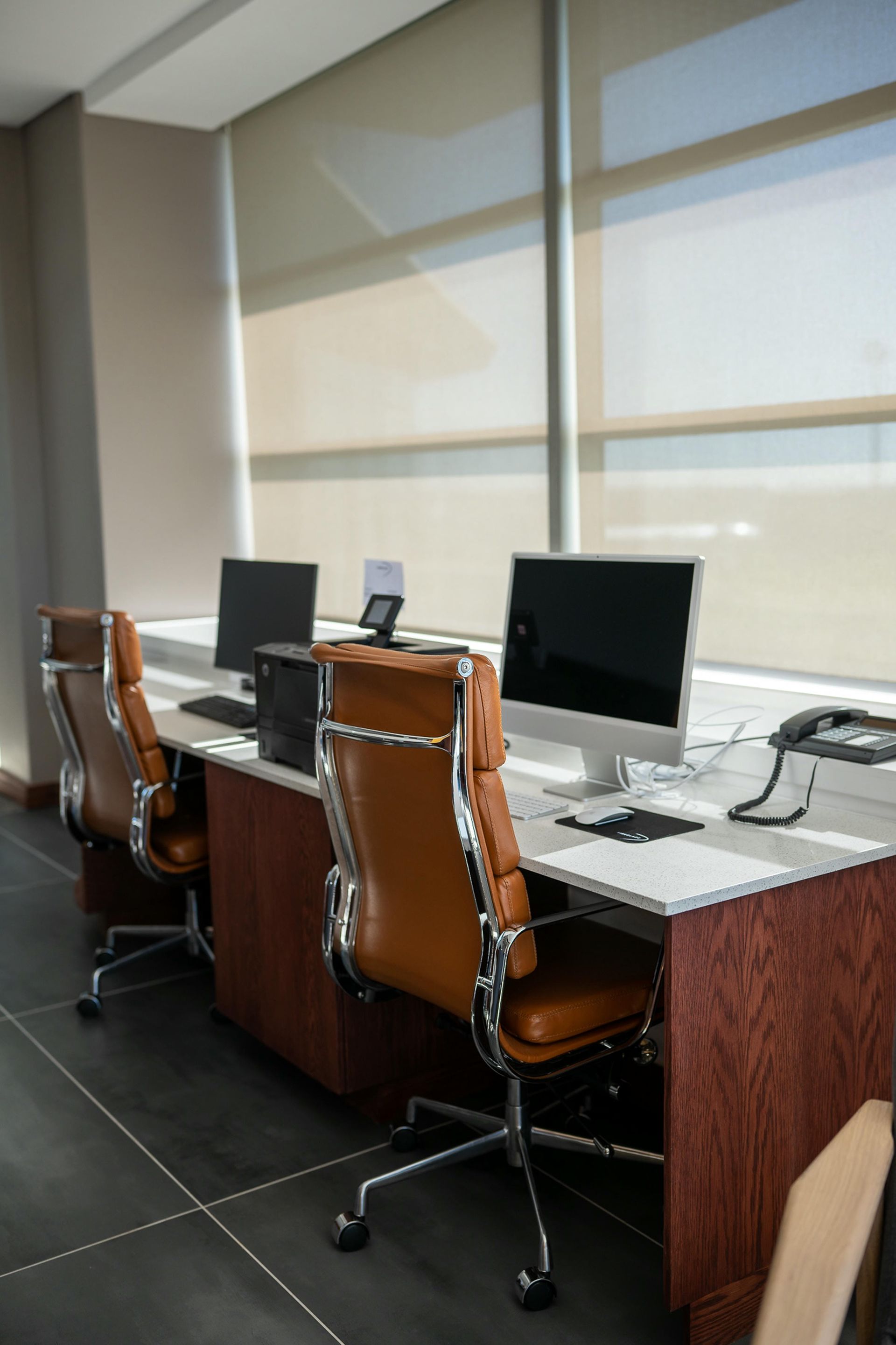 A row of desks with computers and chairs in an office.