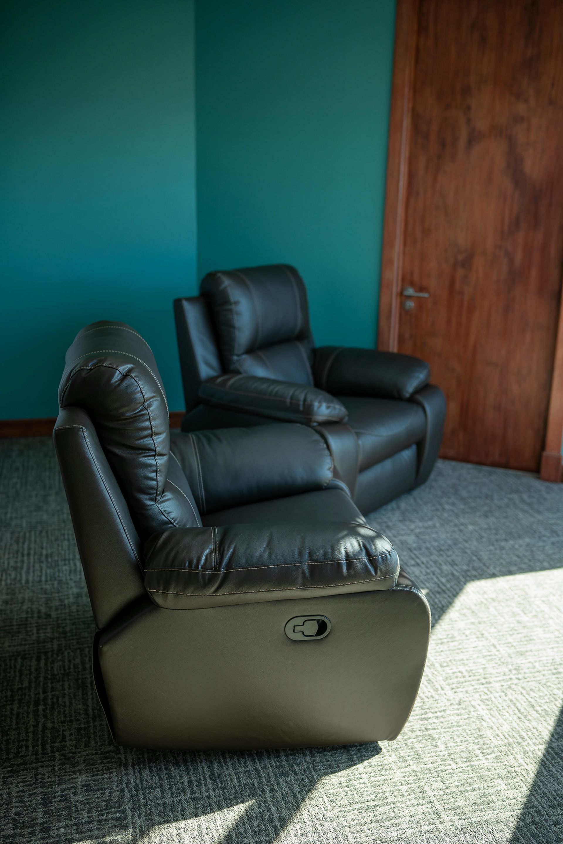 Two black leather recliner chairs are sitting in a corner of a room.