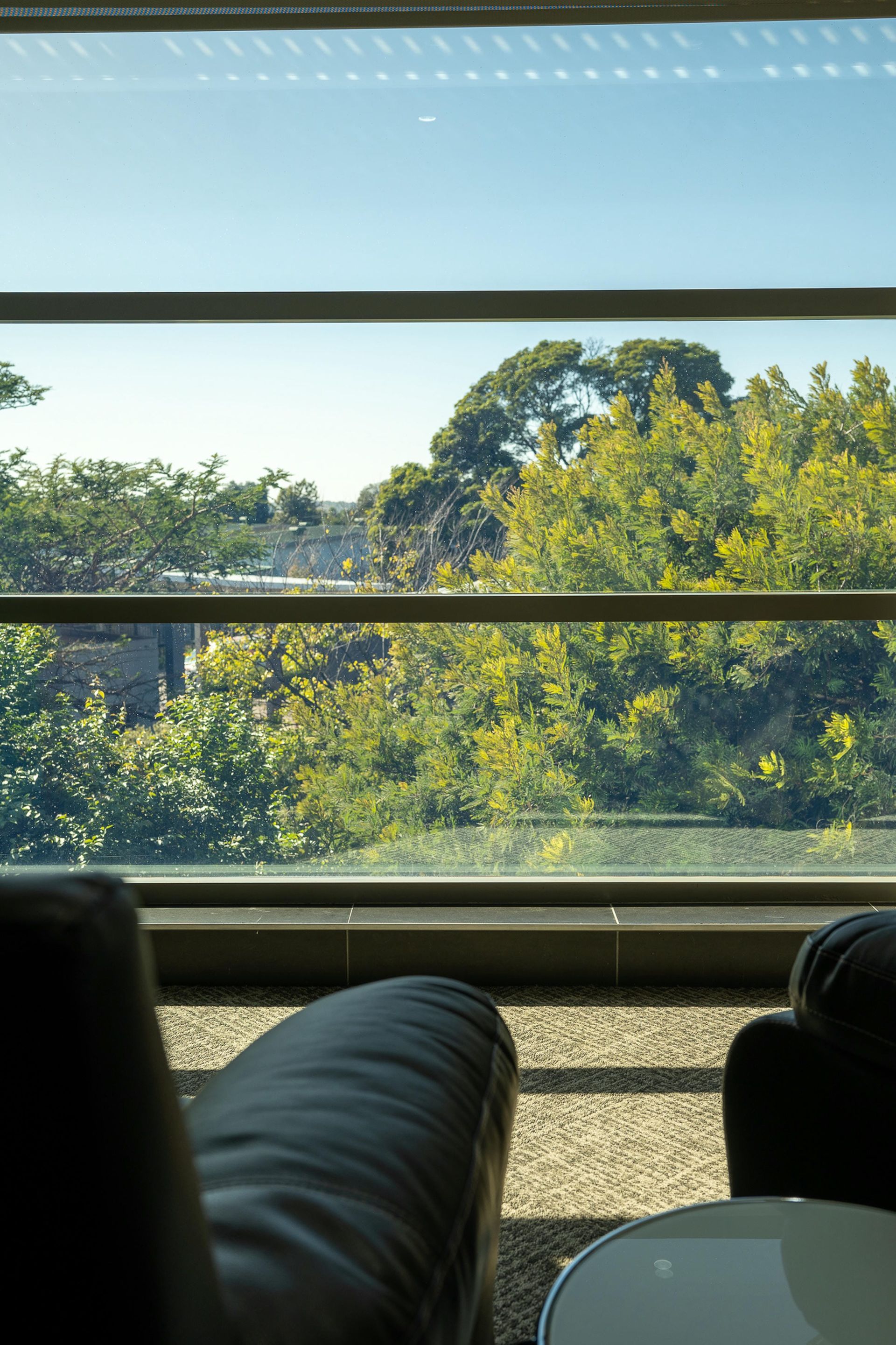 A chair and a table are sitting in front of a window with a view of trees.