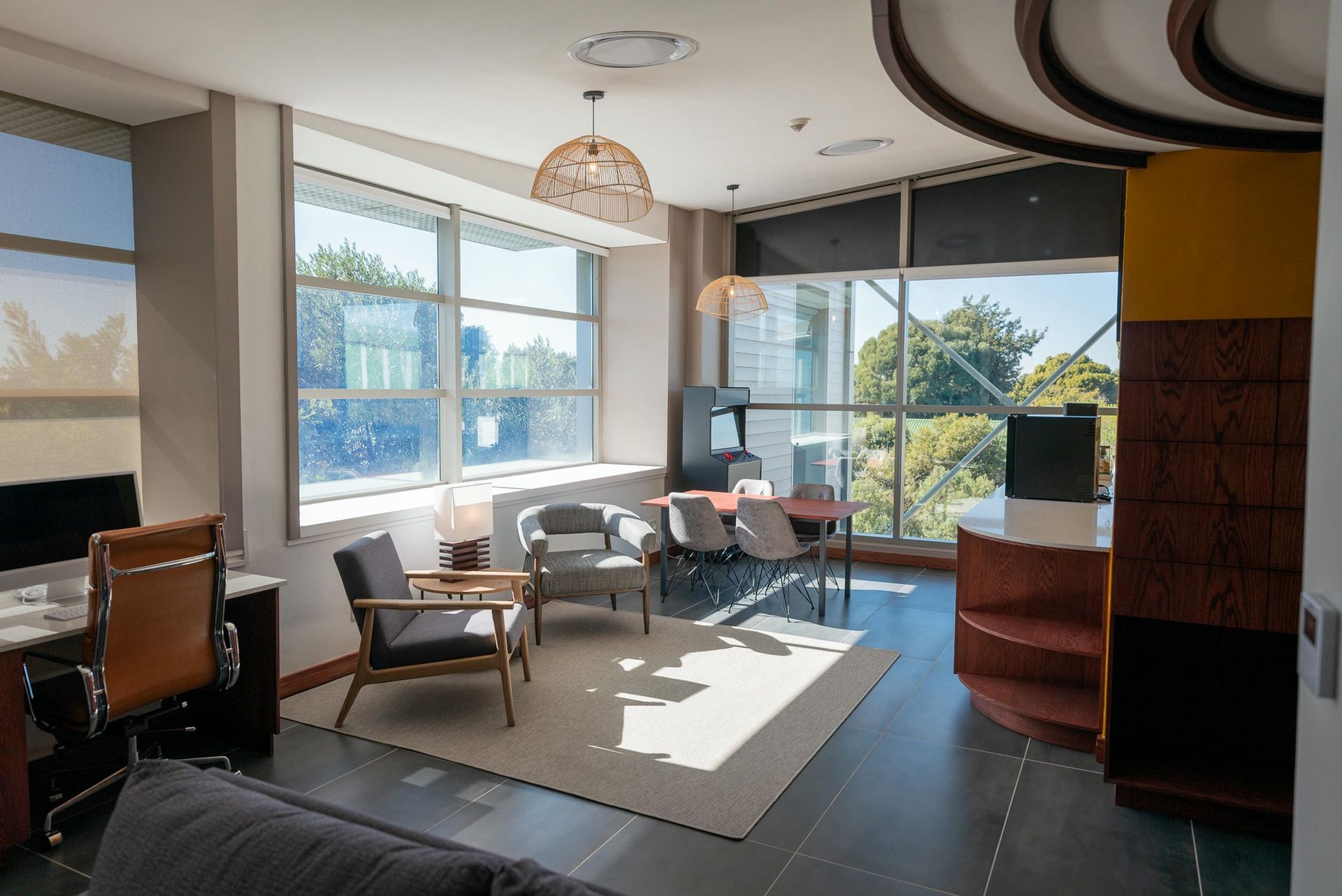 A living room with a couch , chairs , a desk and a large window.