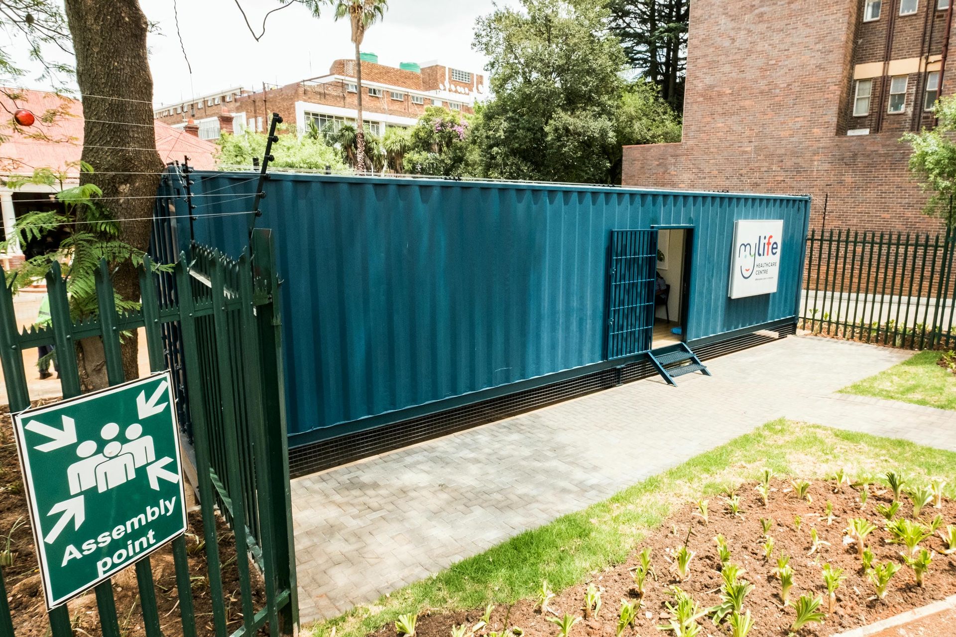 A blue shipping container is sitting in front of a fence.