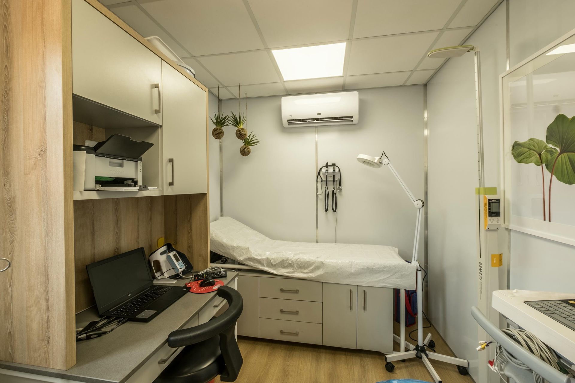 A doctor 's office with a desk and a bed.