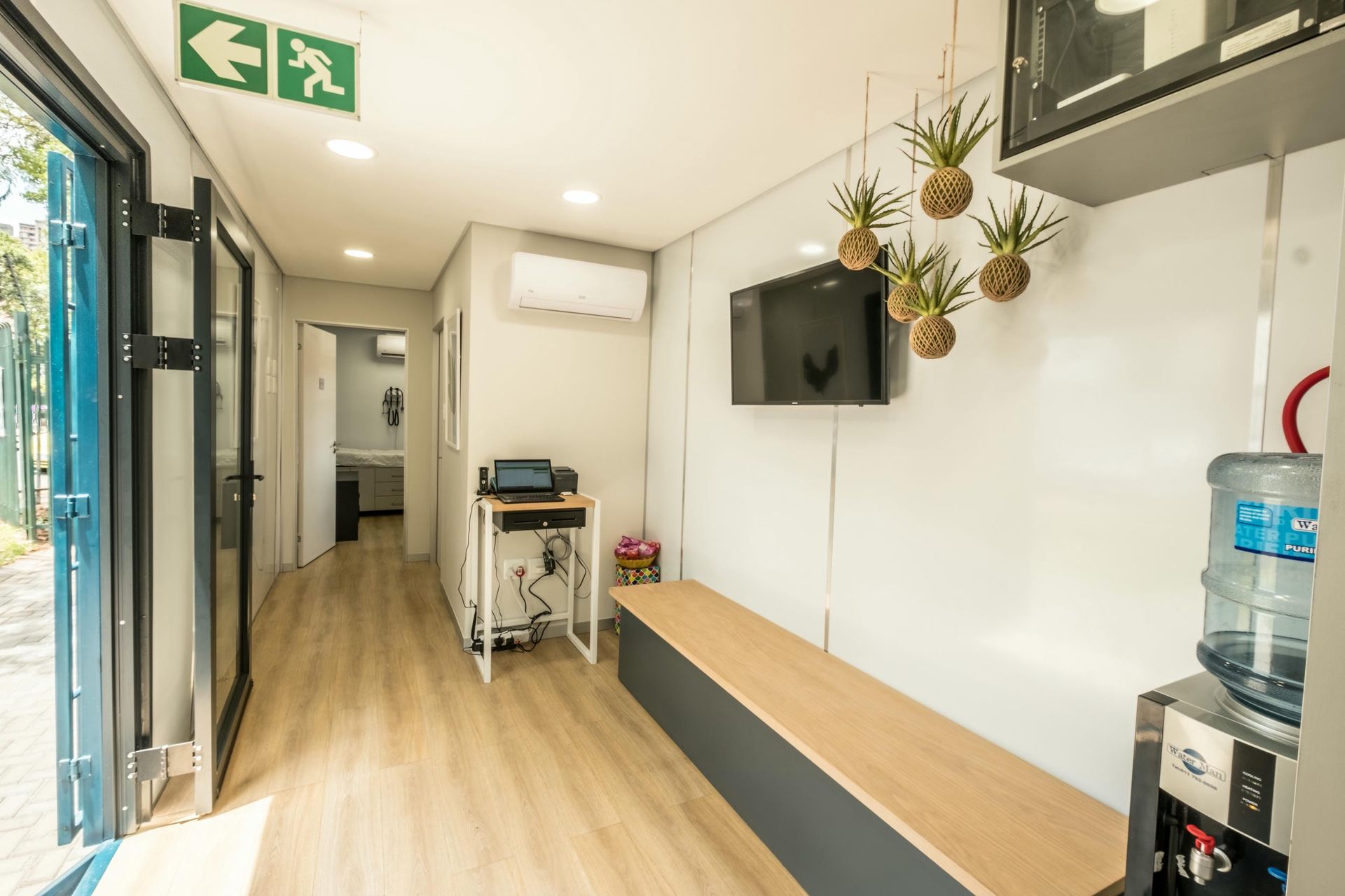 A waiting room with a bench and a tv on the wall.
