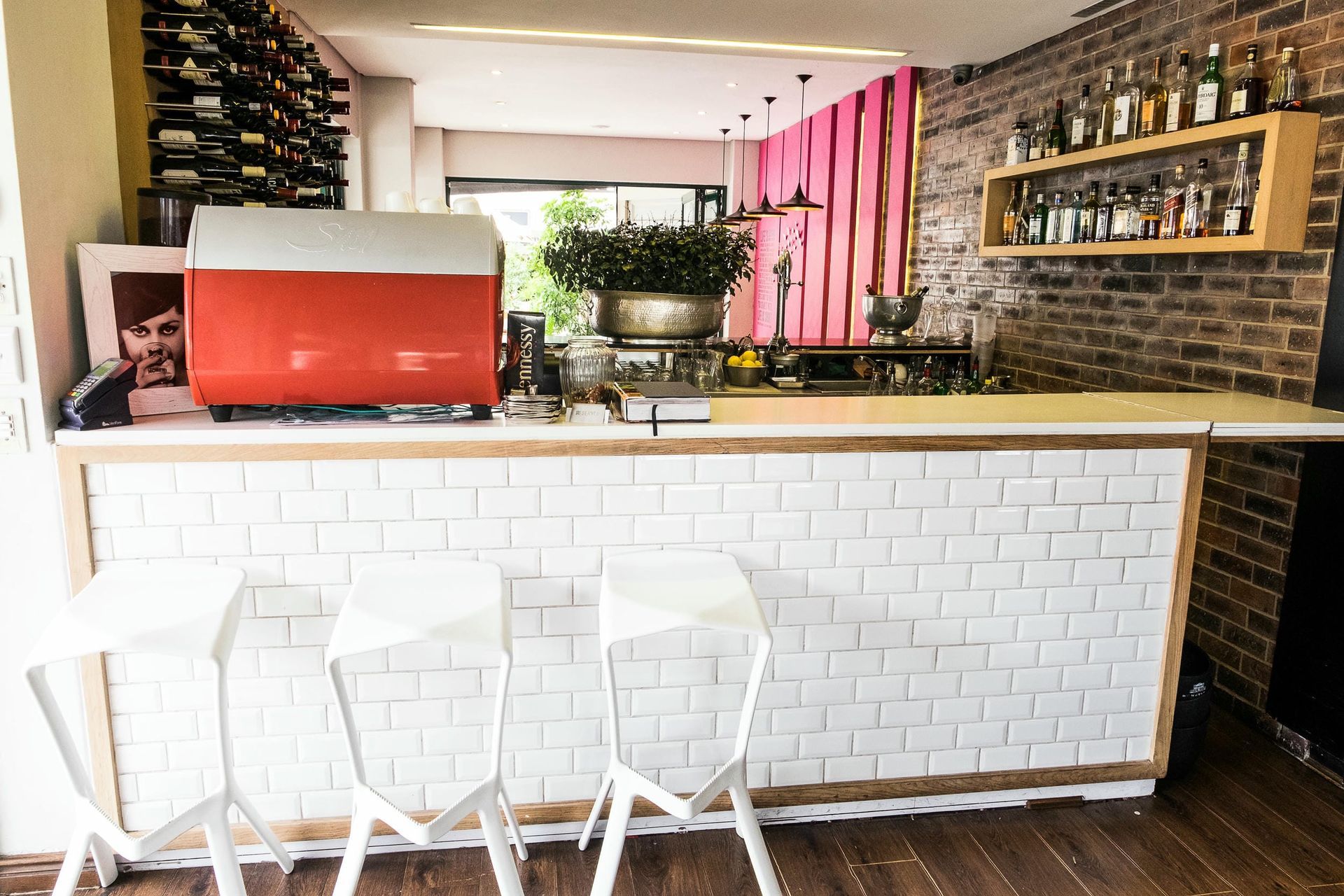 A bar with white stools and a red coffee machine