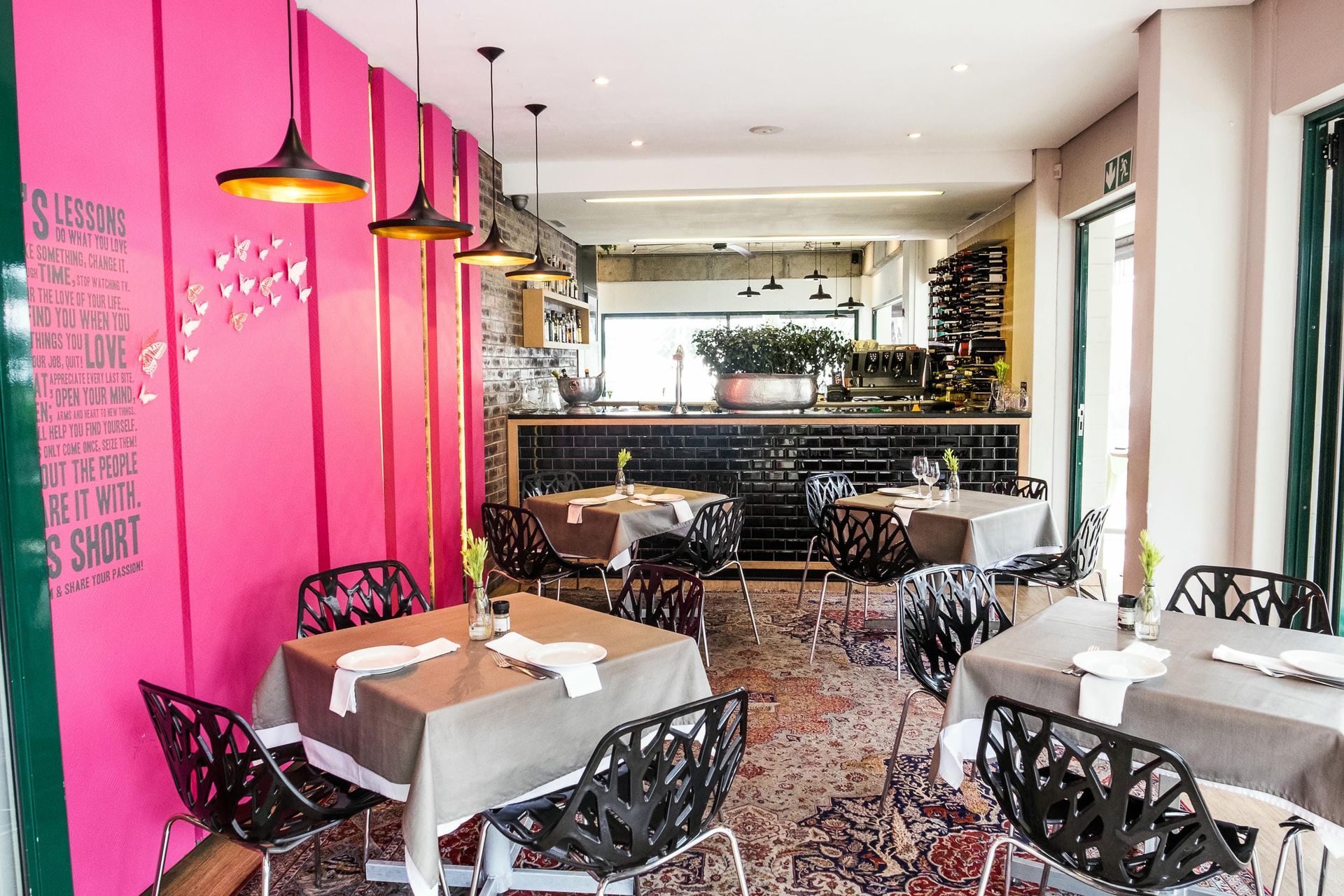 A restaurant with tables and chairs and a pink wall.