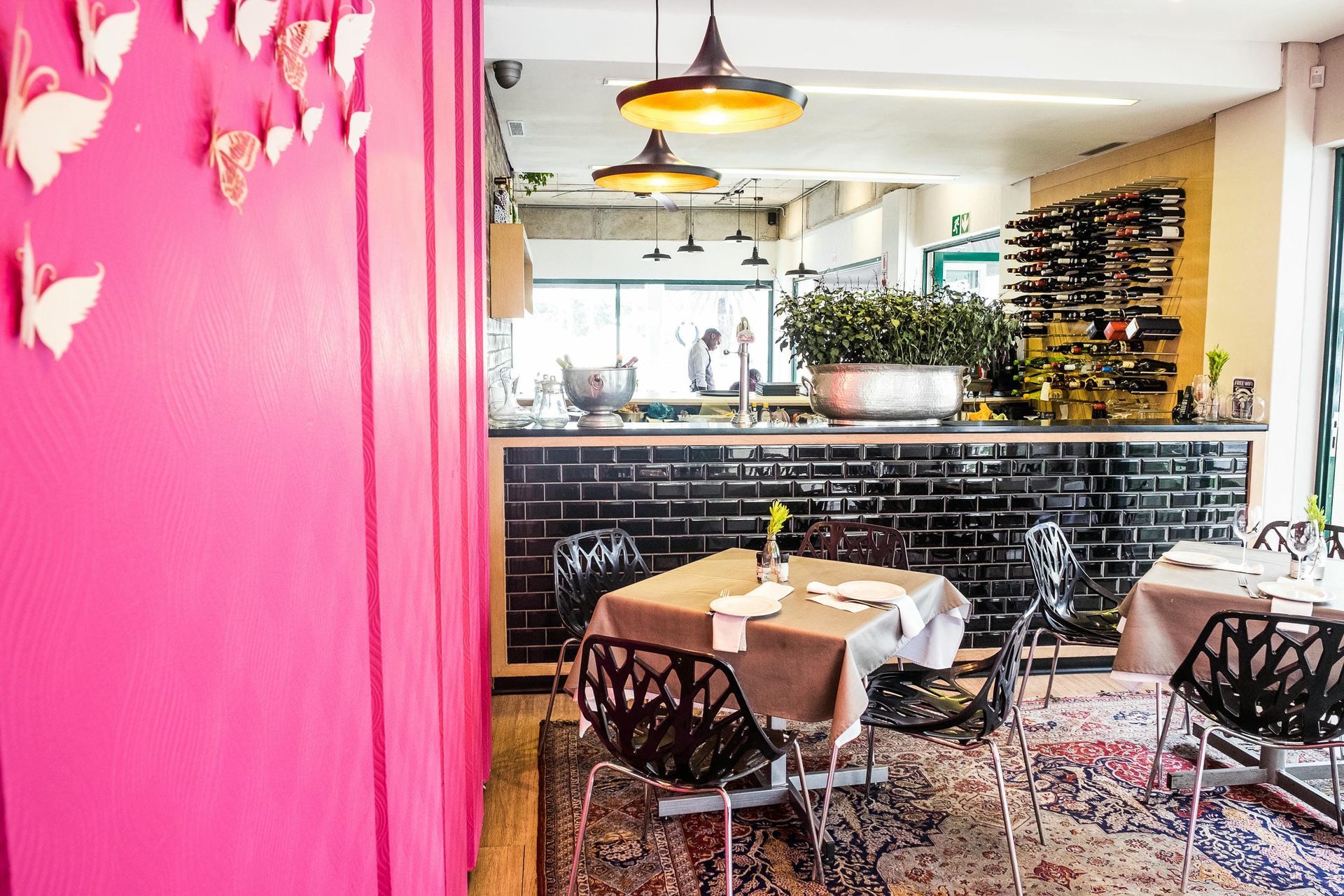 A restaurant with tables and chairs and a pink wall.