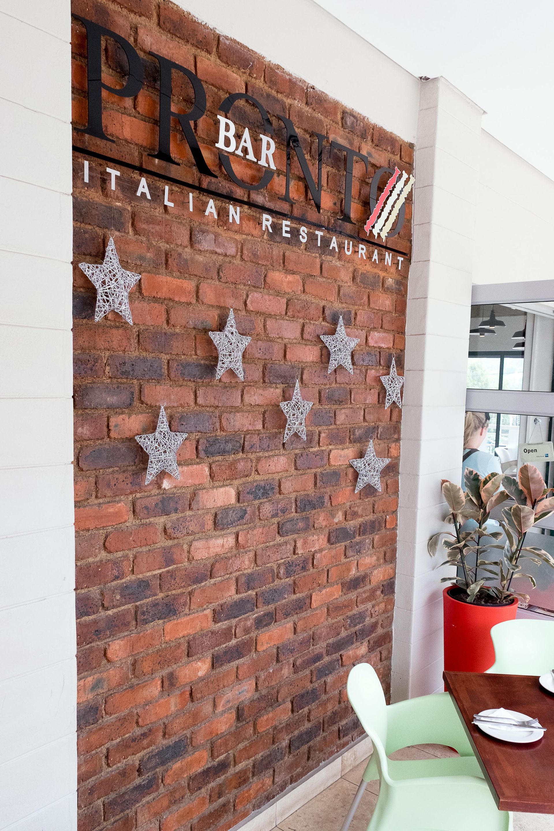 A brick wall with a sign on it and a table and chairs in front of it.