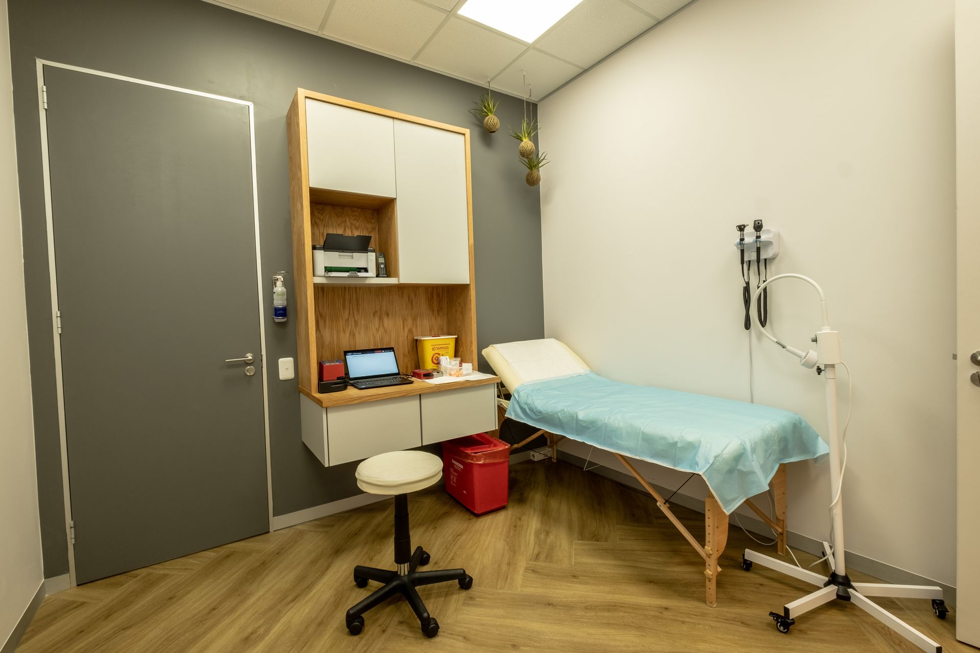 A doctor 's office with a bed , desk and stool.