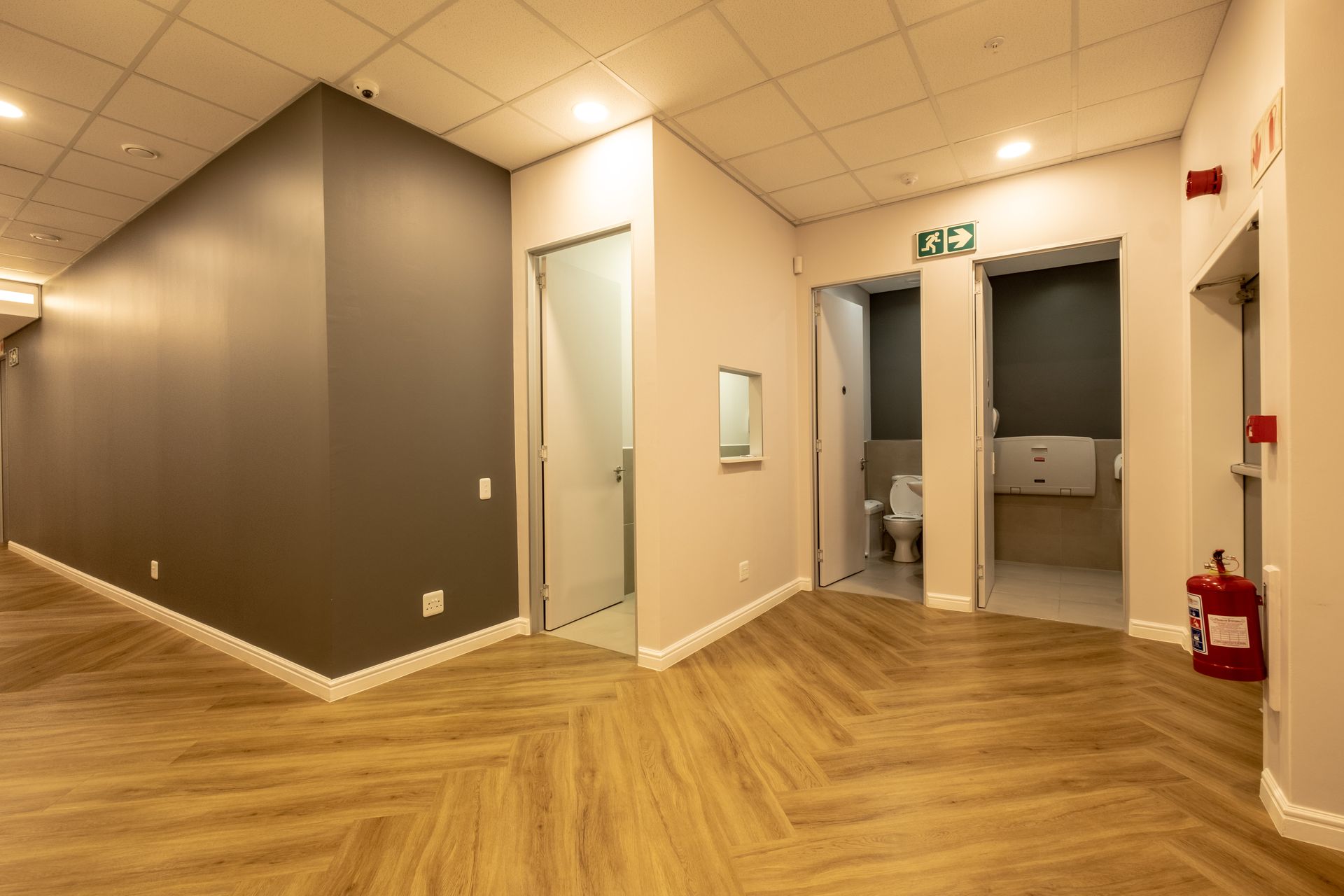 An empty hallway with wooden floors and a fire extinguisher.