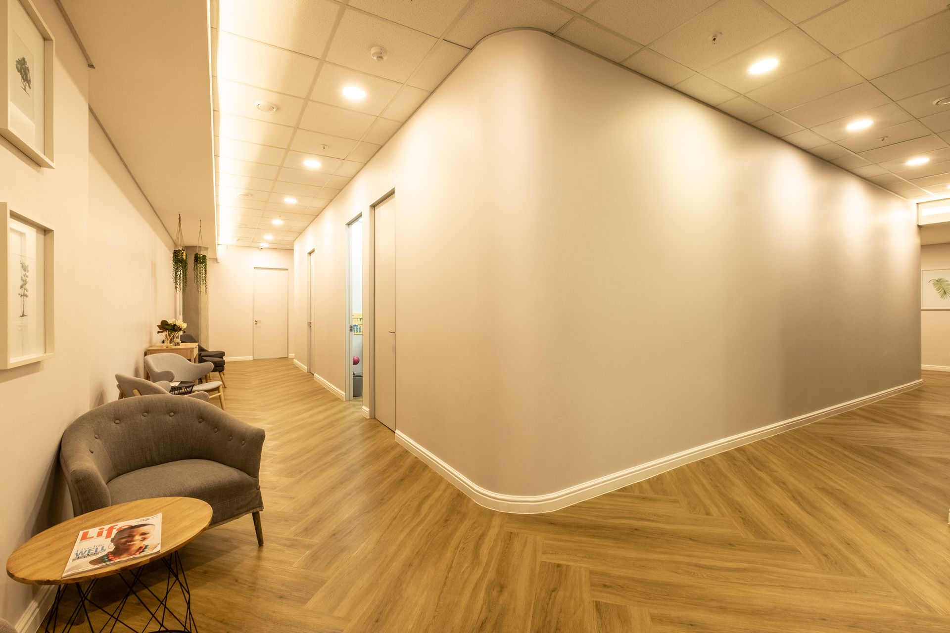 A long hallway with chairs and a table in it.