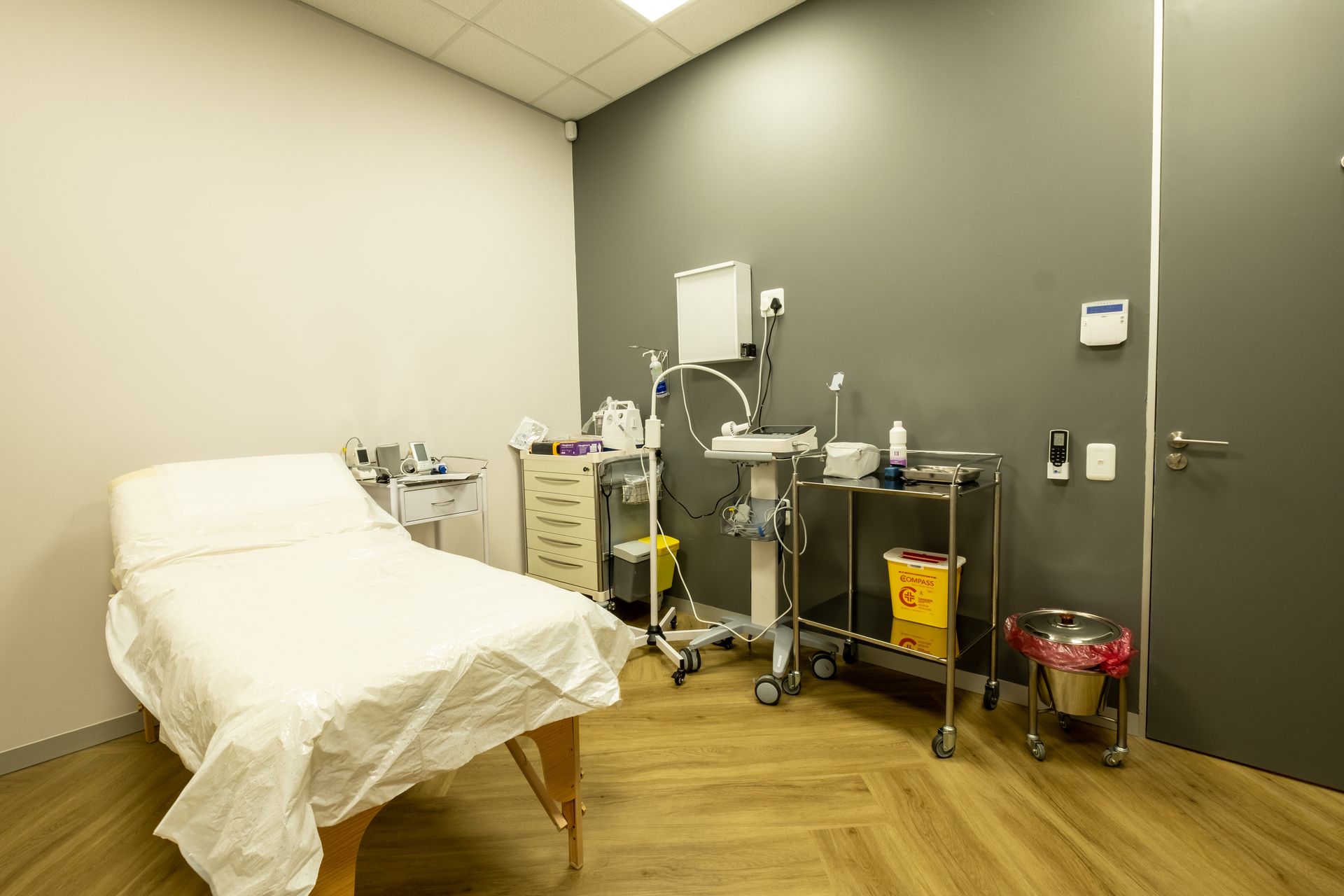 A doctor 's office with a bed and medical equipment.