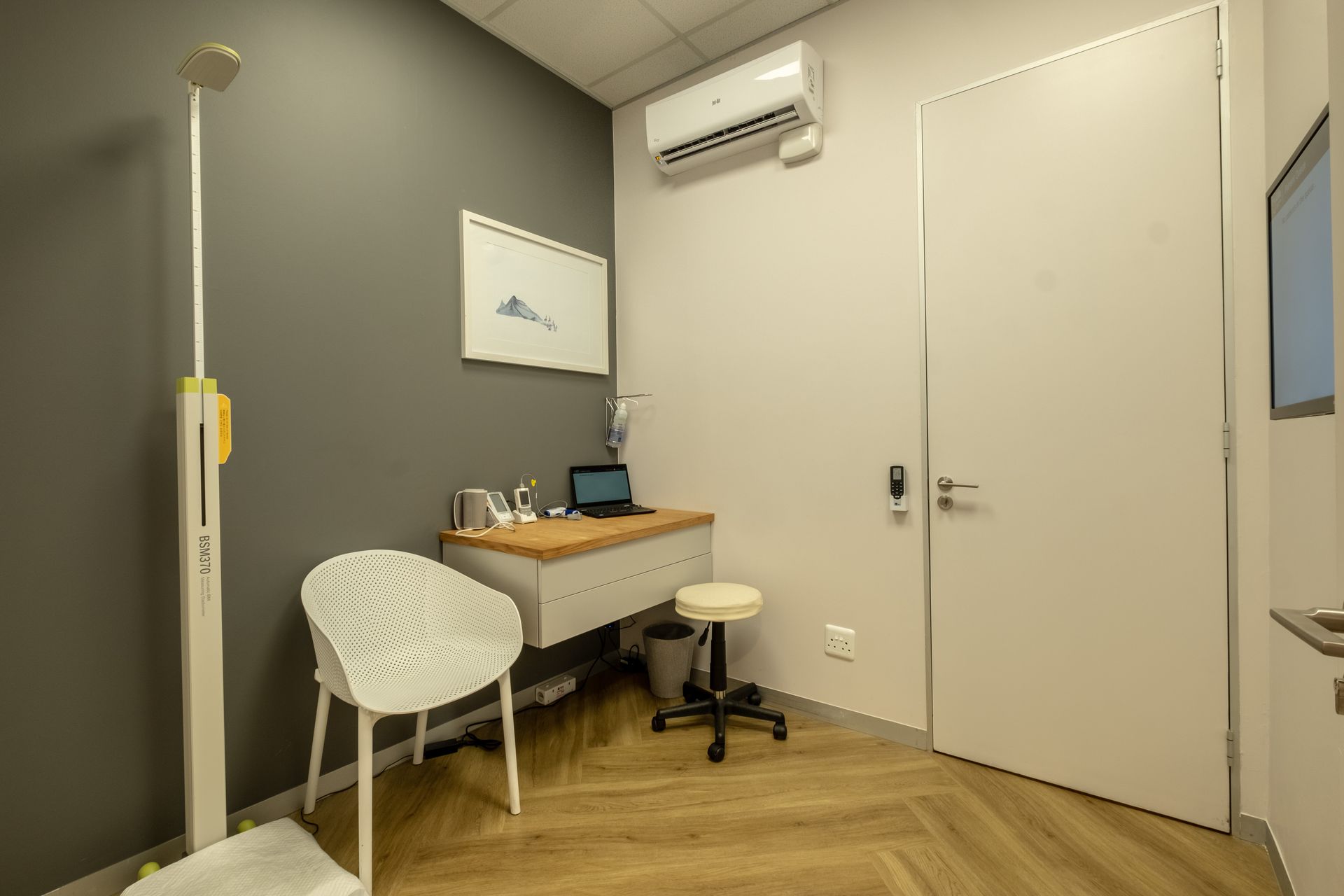 A doctor 's office with a desk , chair , and scale.