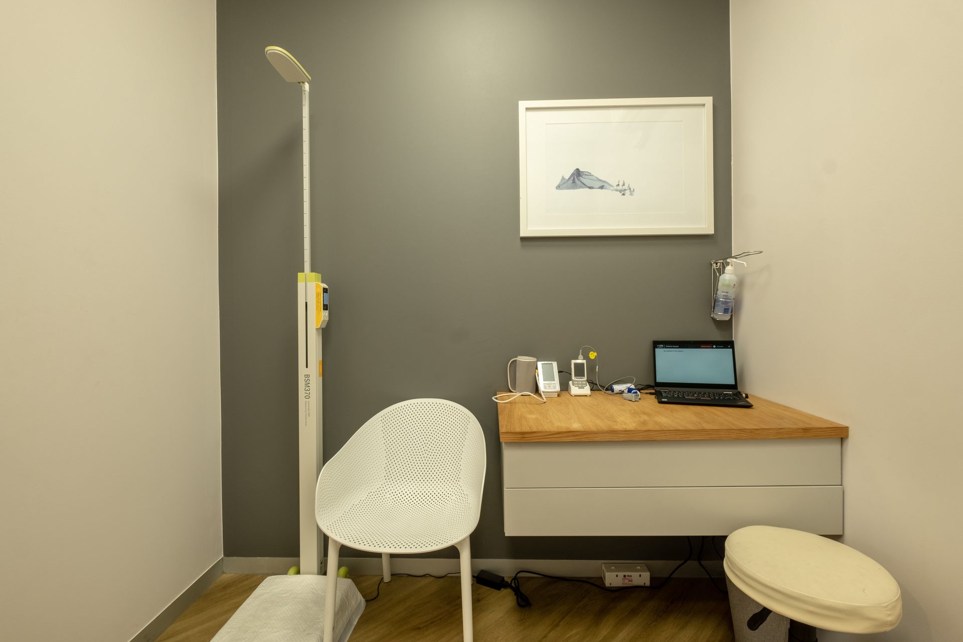 A doctor 's office with a desk , chair and laptop.