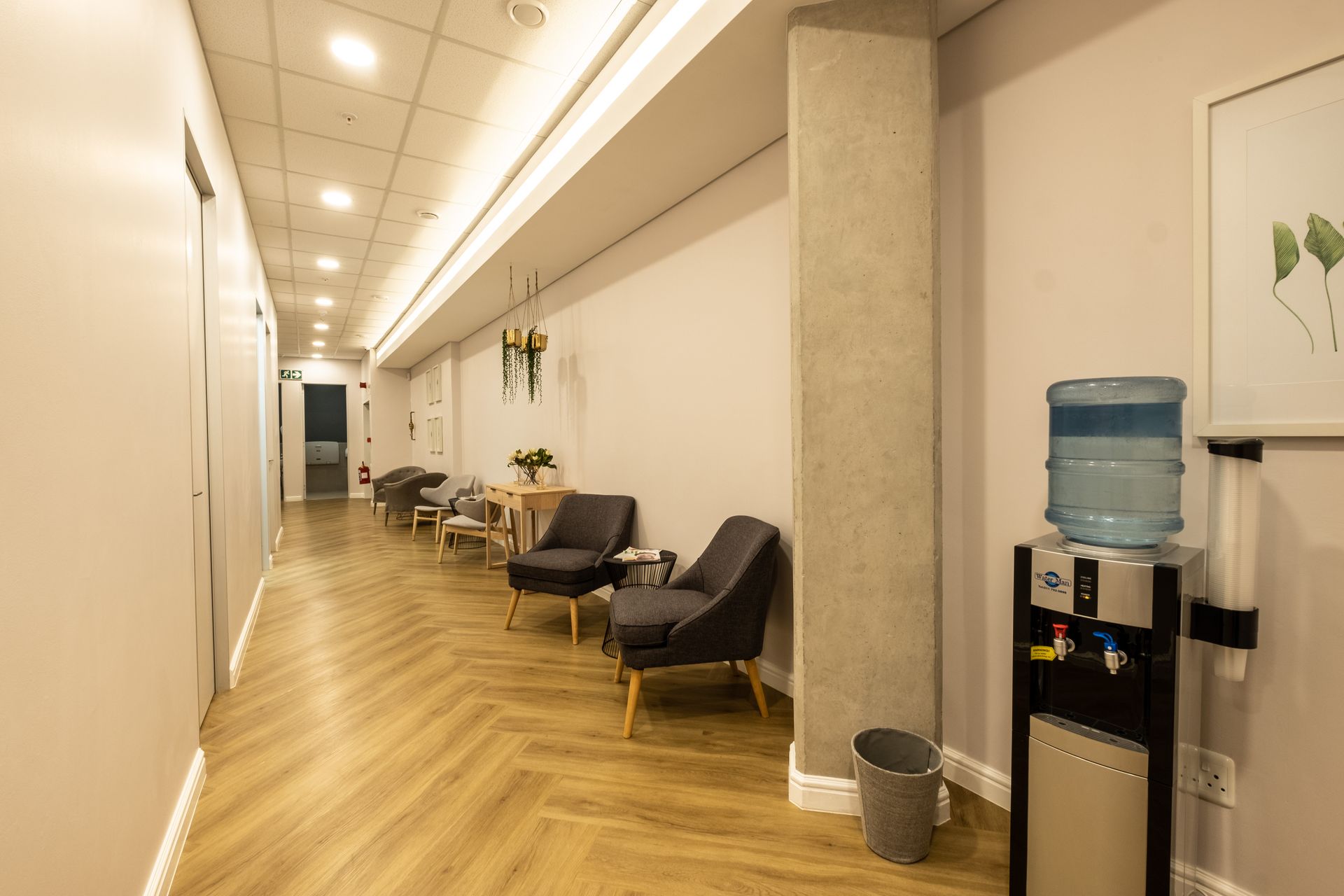 A long hallway with chairs and a water dispenser.