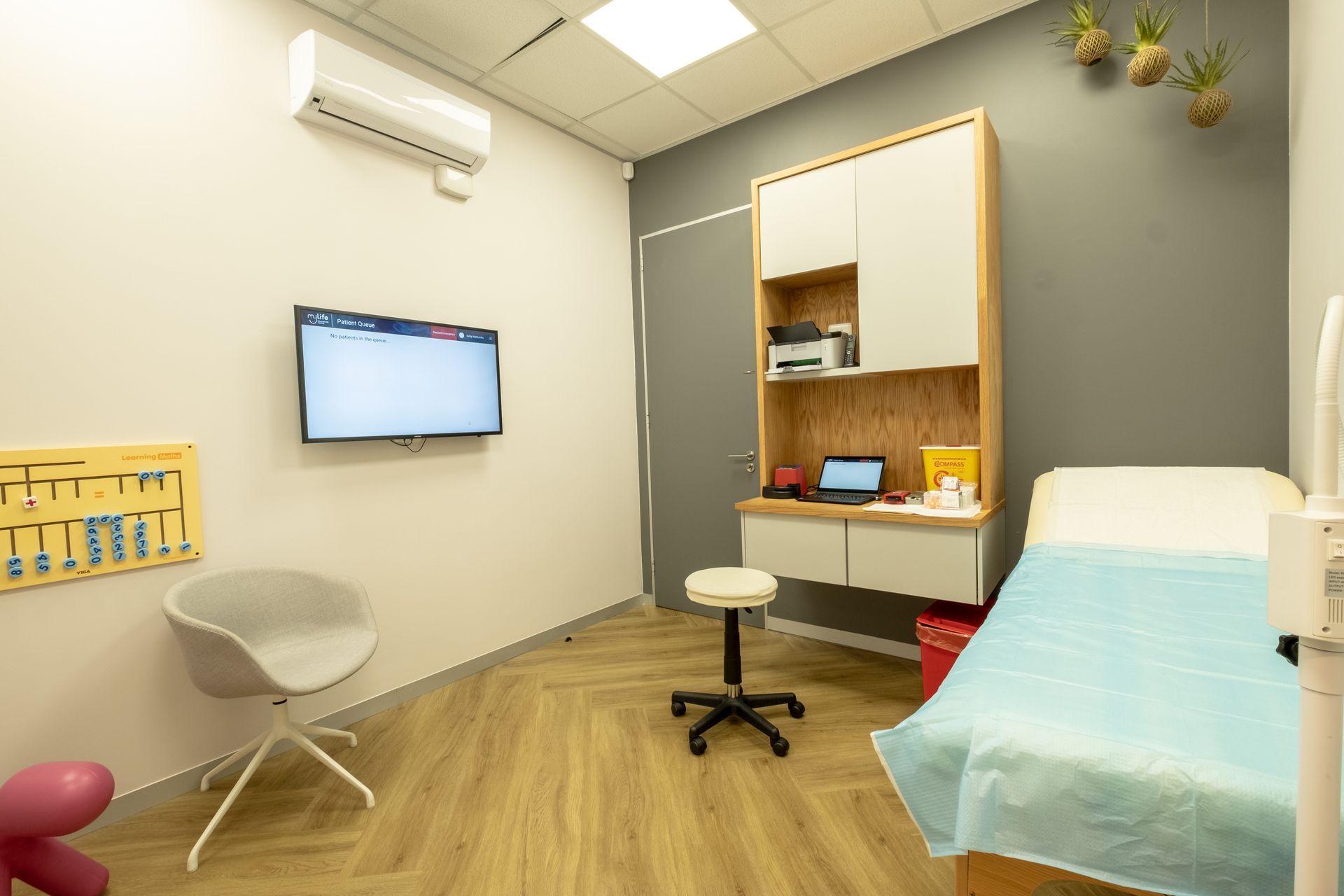 A doctor 's office with a bed , desk , chair and television.