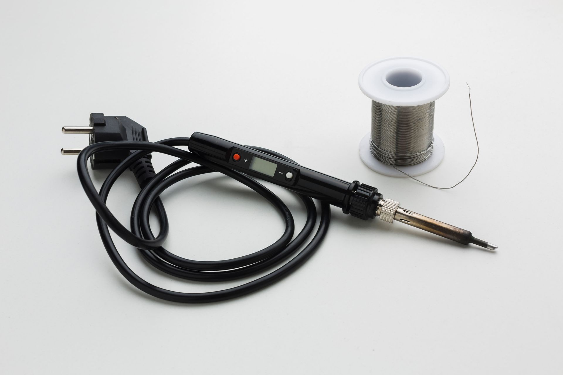 Soldering iron with digital display and a spool of solder wire, on a white background.
