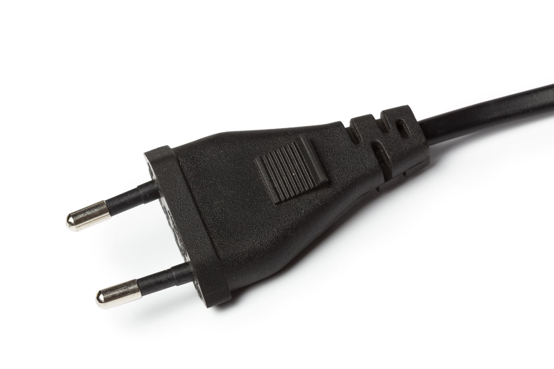 Black two-prong electrical plug with metallic pins, angled on a white surface.