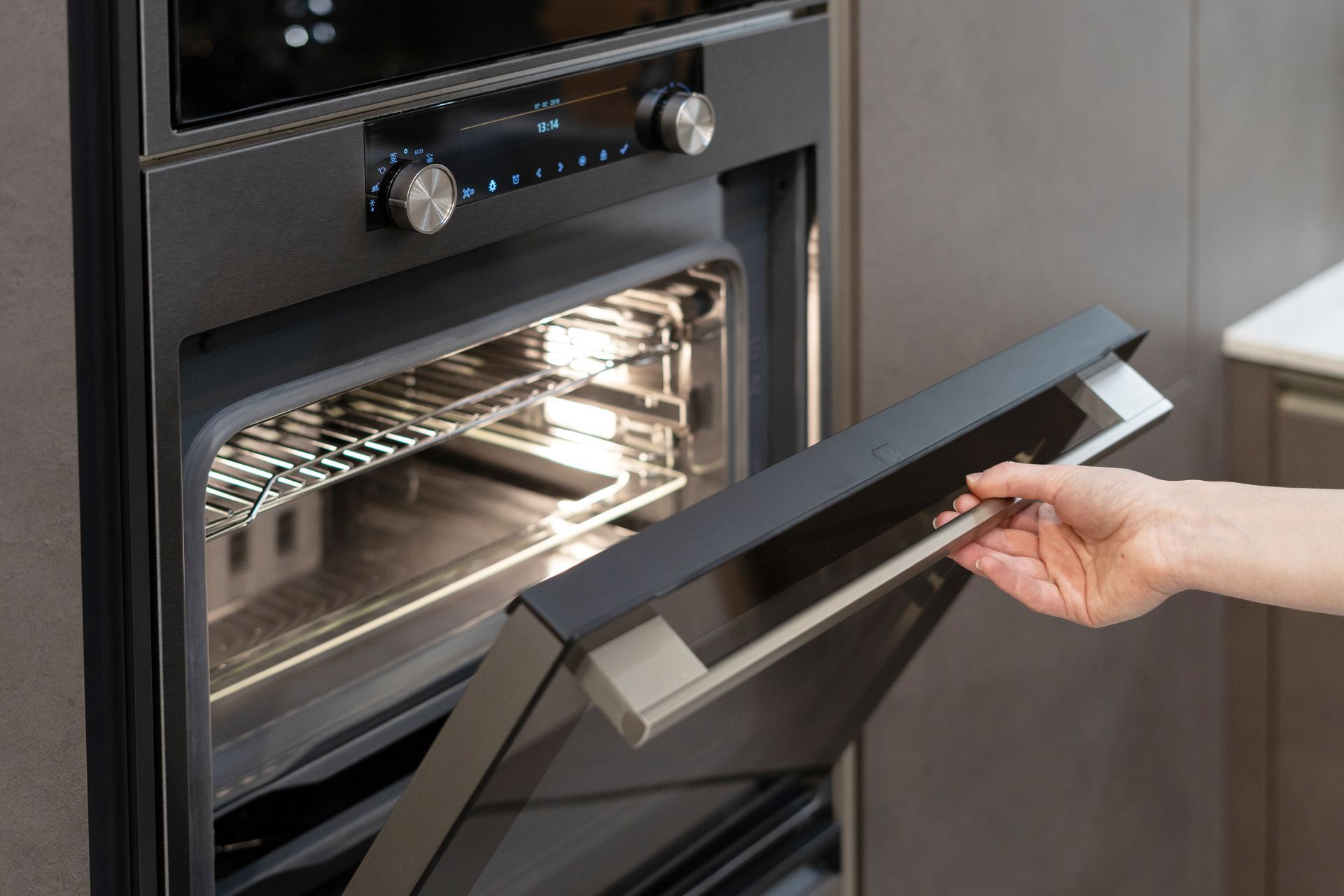 Person opening a dark oven door; interior light illuminates oven racks. Person opening a dark oven door; interior light illuminates oven racks.