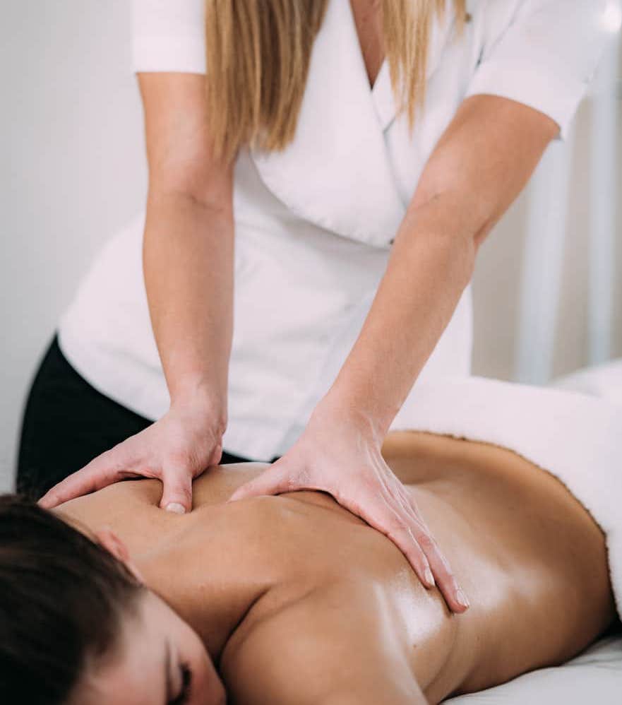 Massage therapist giving back massage to a client on a treatment table