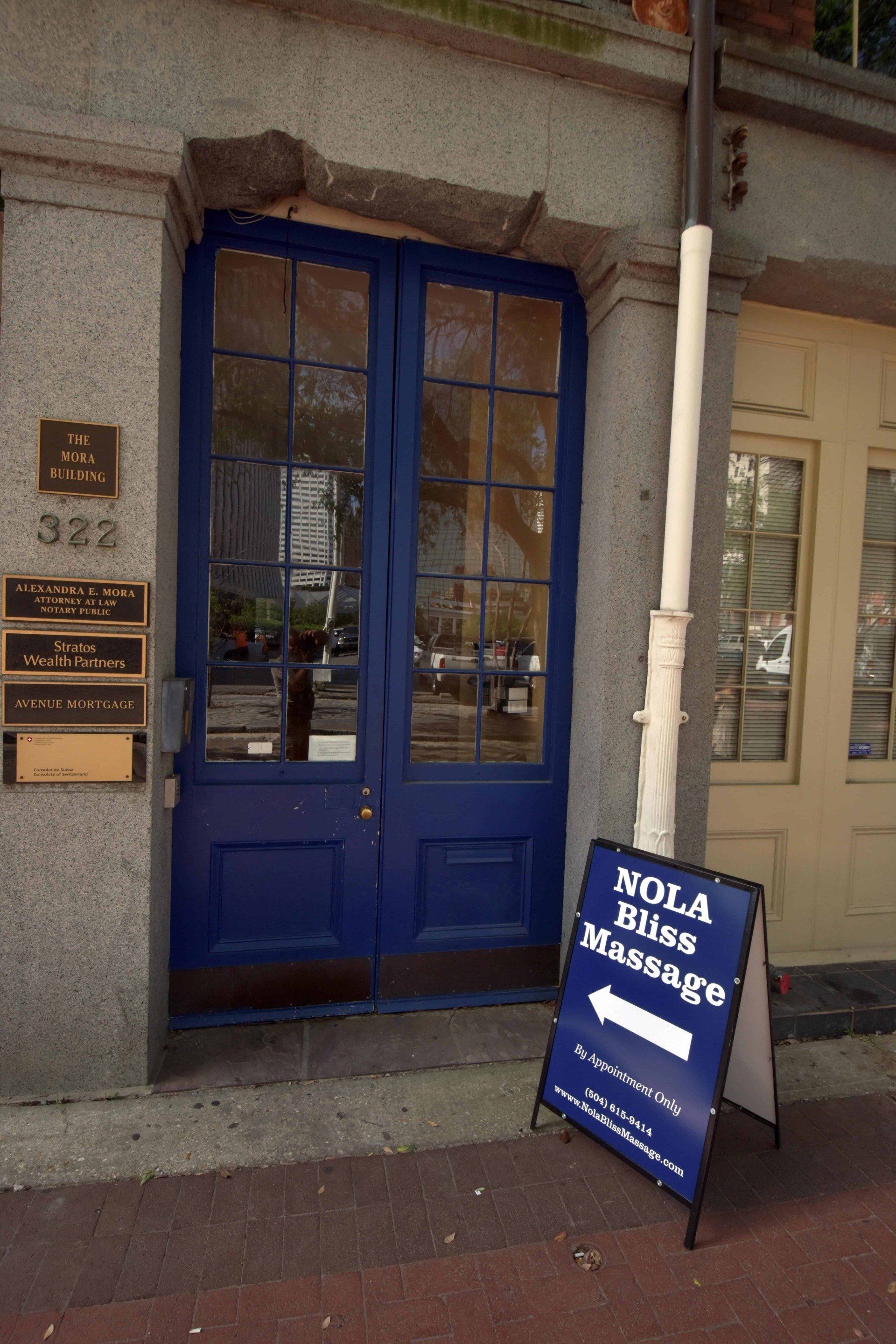 Blue storefront door with a sidewalk sign for a massage business outside.