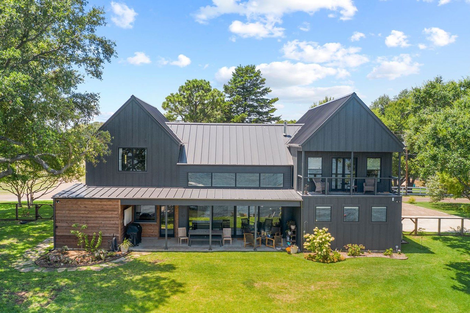 A large house with a lot of windows is sitting on top of a lush green field.