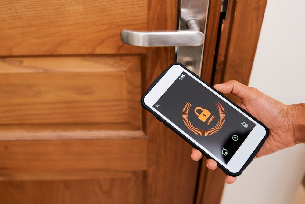 A Person Is Holding A Cell Phone In Front Of A Door — SPL Security Solutions In Northern, NSW