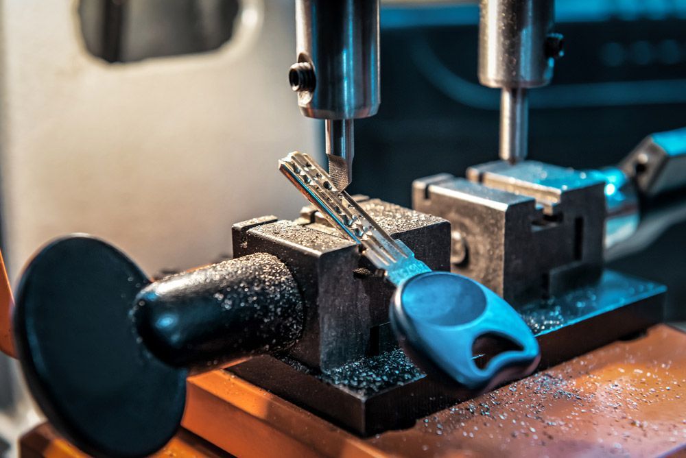 A Key Is Being Cut On A Machine In A Locksmith Shop — SPL Security Solutions In Coomera, QLD