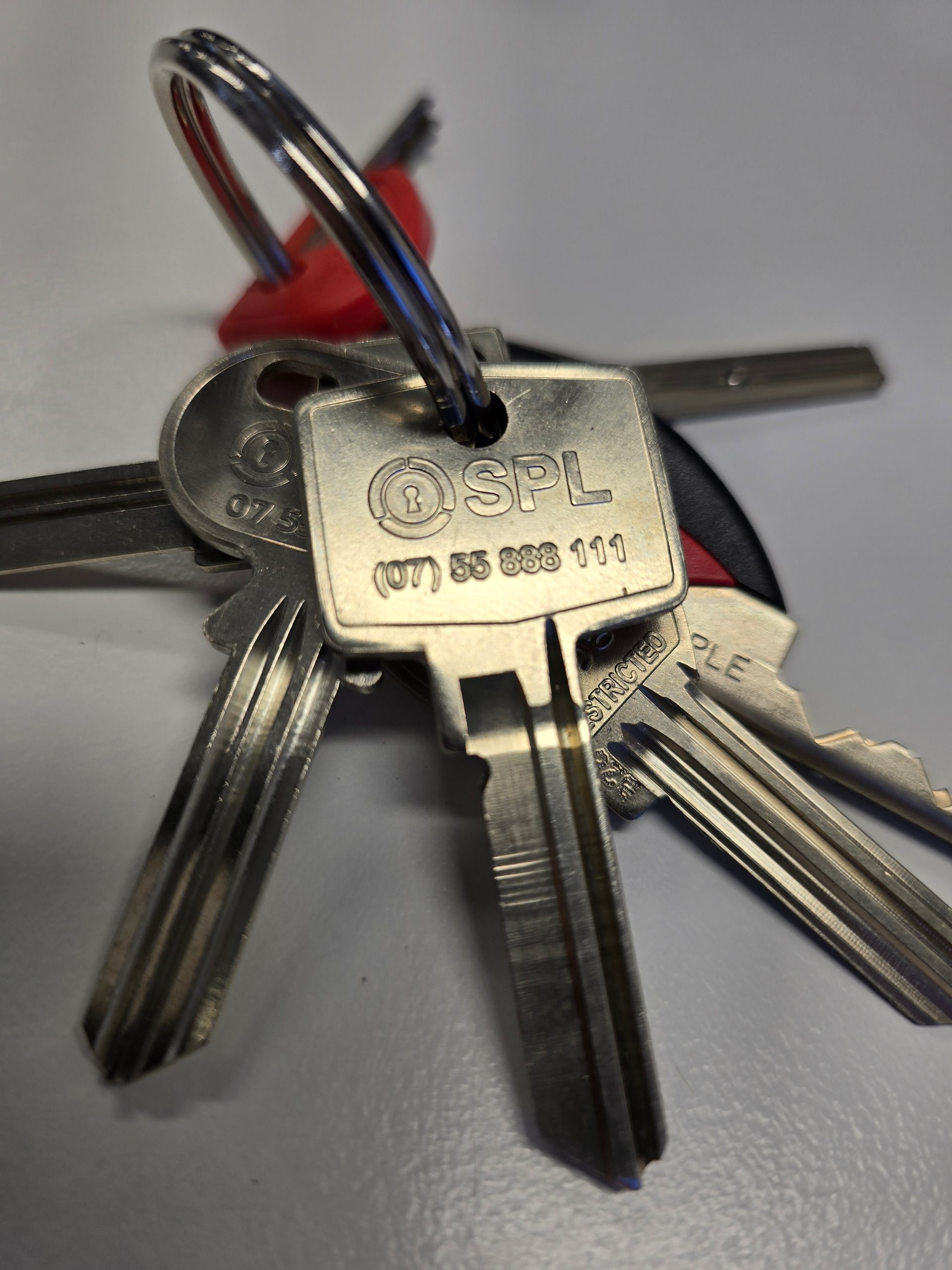 Close-up of a set of metal keys on a keyring with an ‘OSPL’ branded key