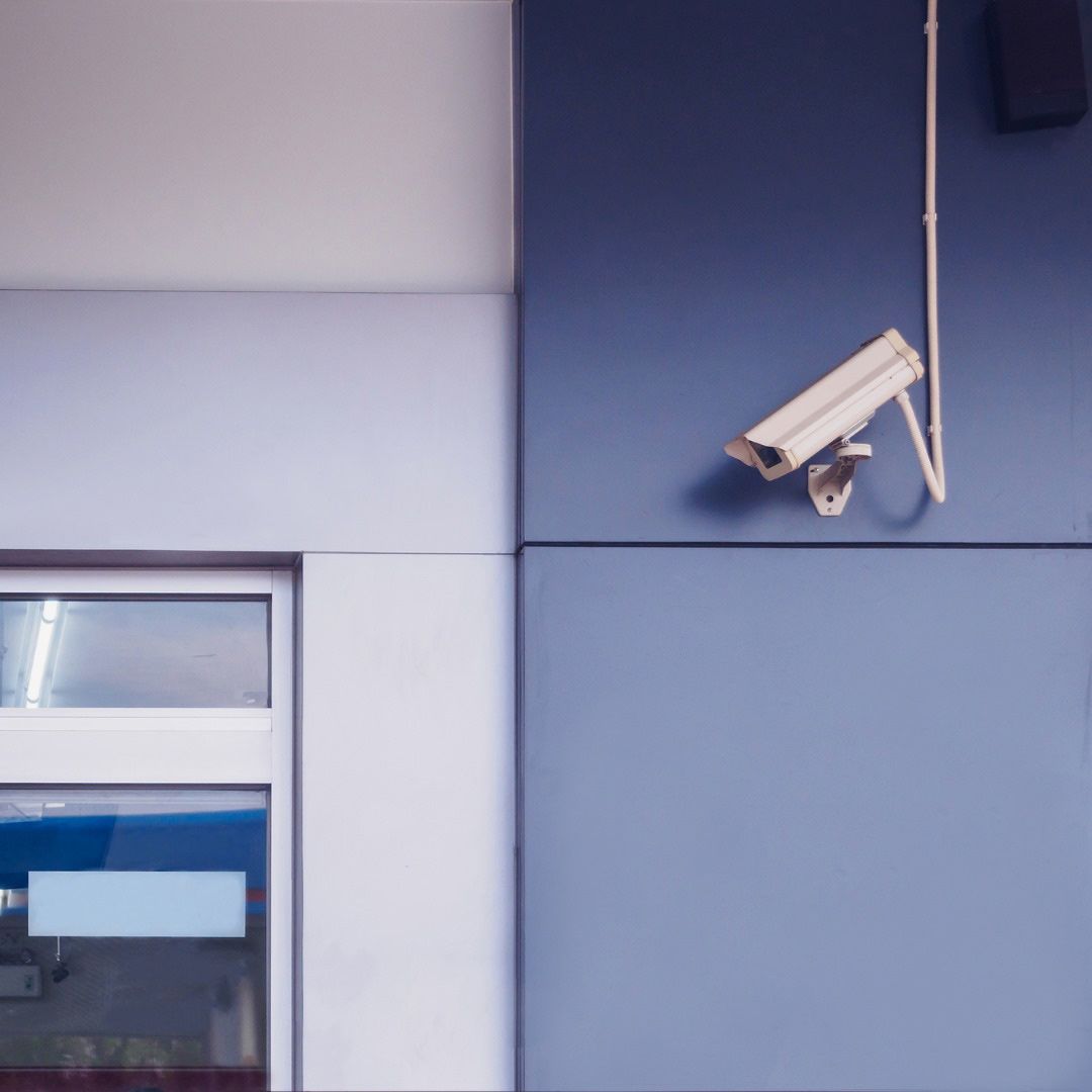 A Security Camera is Hanging From the Side of a Building — SPL Security Solutions In Gold Coast, QLD