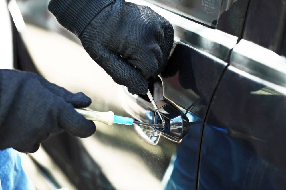 A Person Wearing Black Gloves Is Trying To Open A Car Door With A Pair Of Pliers — SPL Security Solutions In Hope Island, QLD