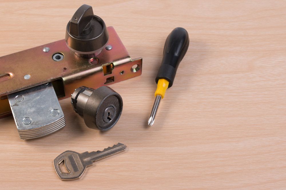 A Lock With A Key And A Screwdriver On A Wooden Table — SPL Security Solutions In Coomera, QLD