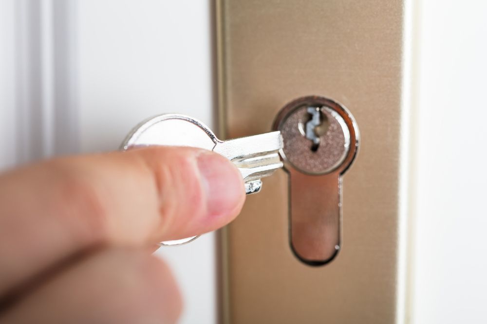 A Person Is Holding A Broken Key In A Door Lock — SPL Security Solutions In Burleigh, QLD