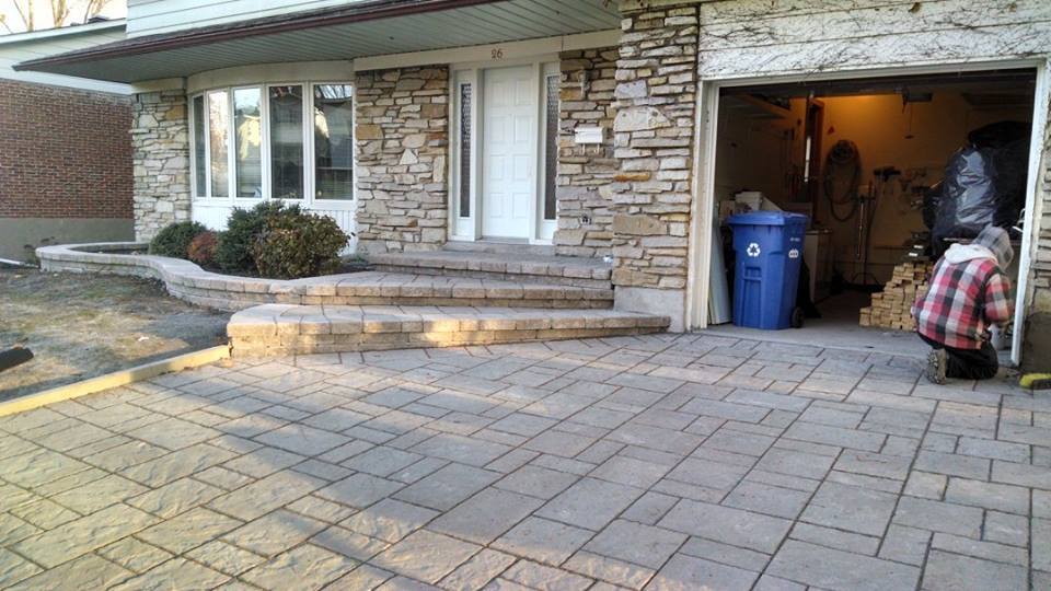 Une personne se tient devant une maison avec une poubelle bleue dans le garage.