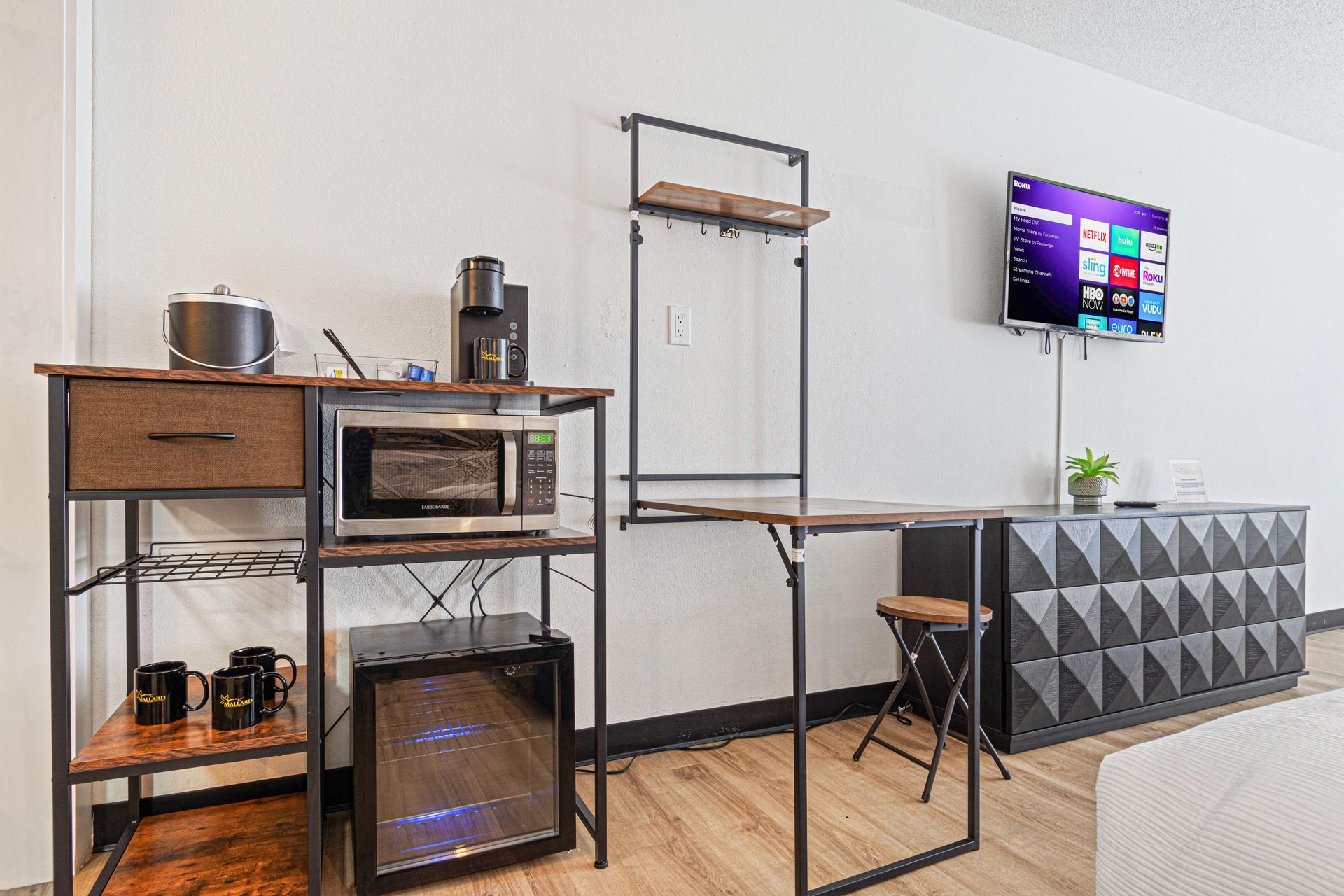 A compact apartment with a kitchenette, microwave, TV, and black accent furniture.