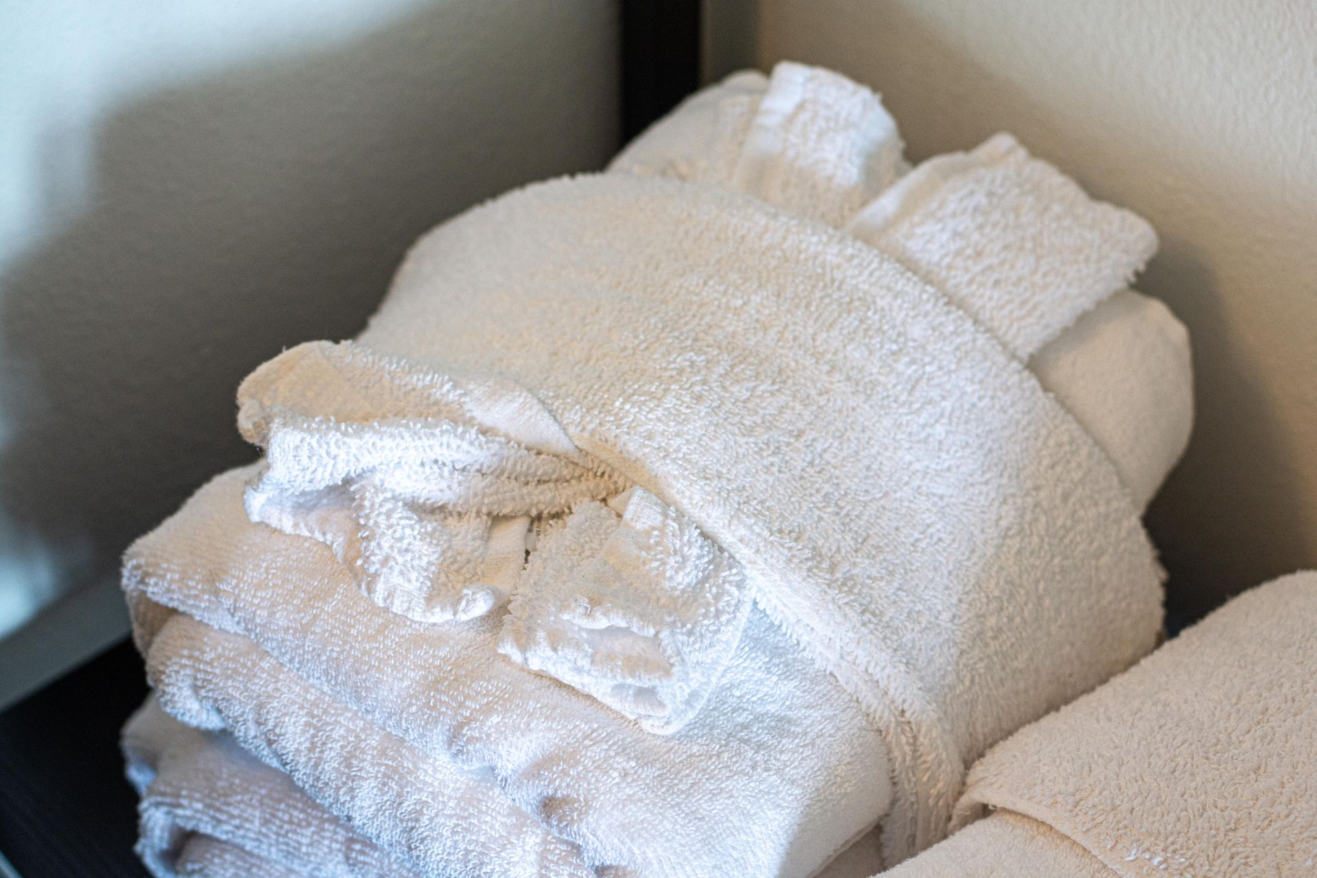 White bathrobes folded neatly on a shelf.