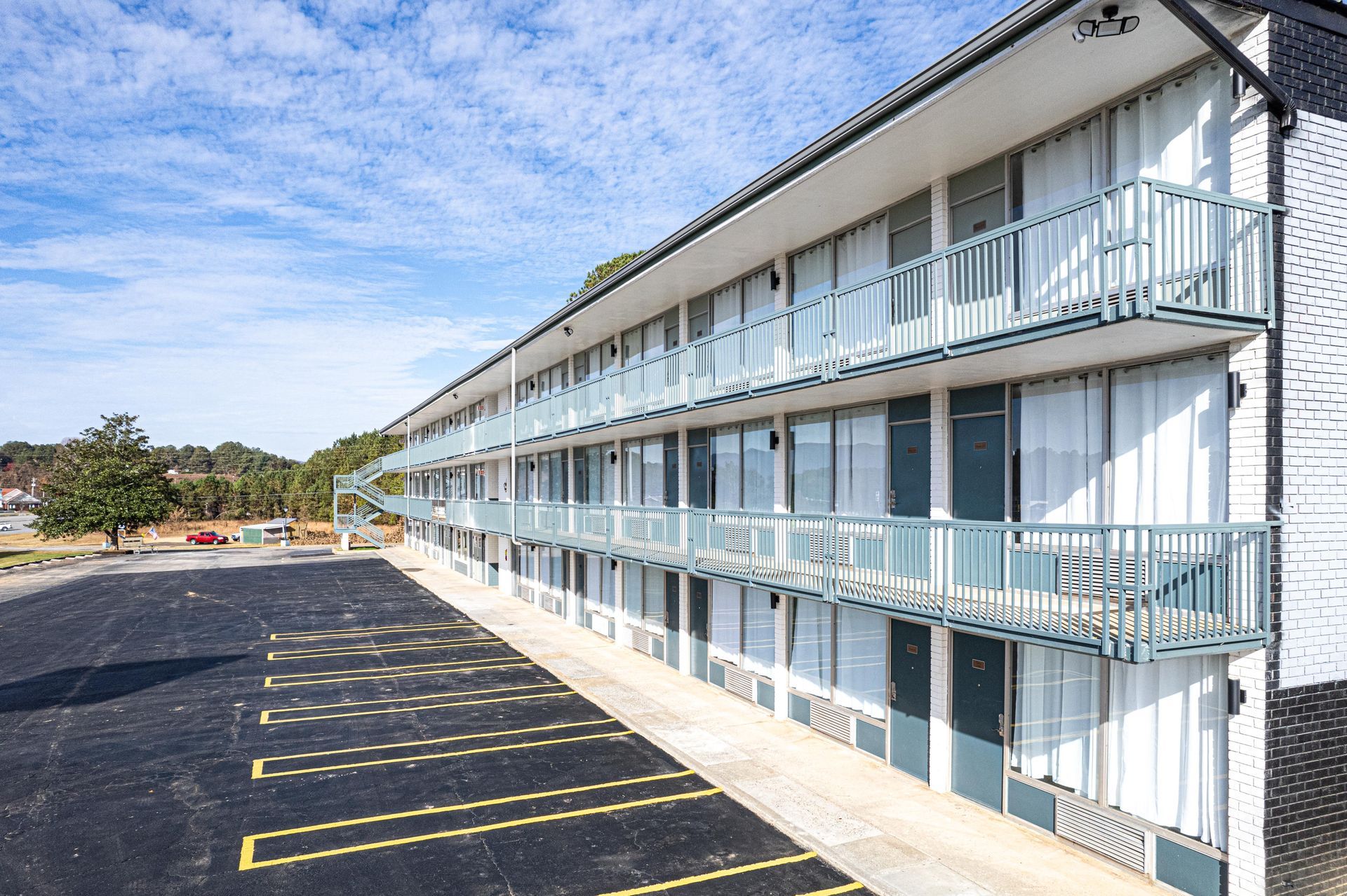 Motel exterior with balconies and parking lot; blue sky.