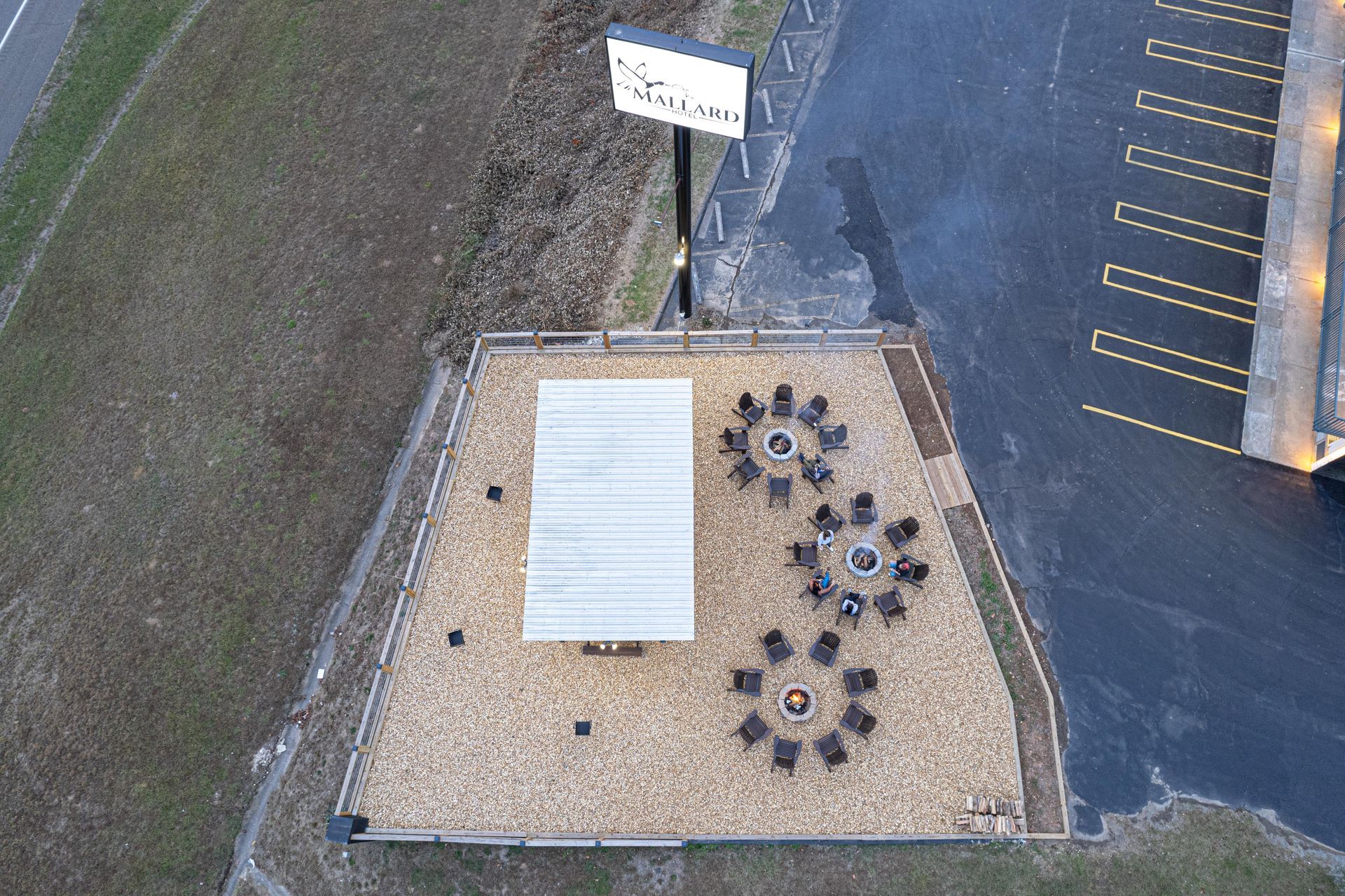 Aerial view of outdoor seating area at Suzio restaurant. Tables with chairs, gravel ground, and a small shelter.