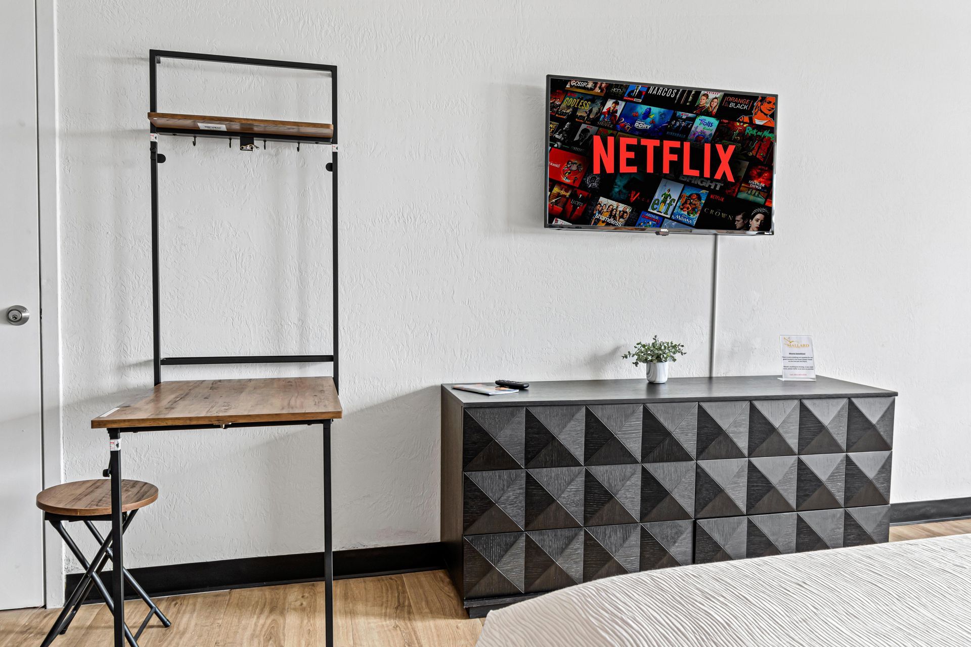 Room with TV showing Netflix above a geometric cabinet and a desk.
