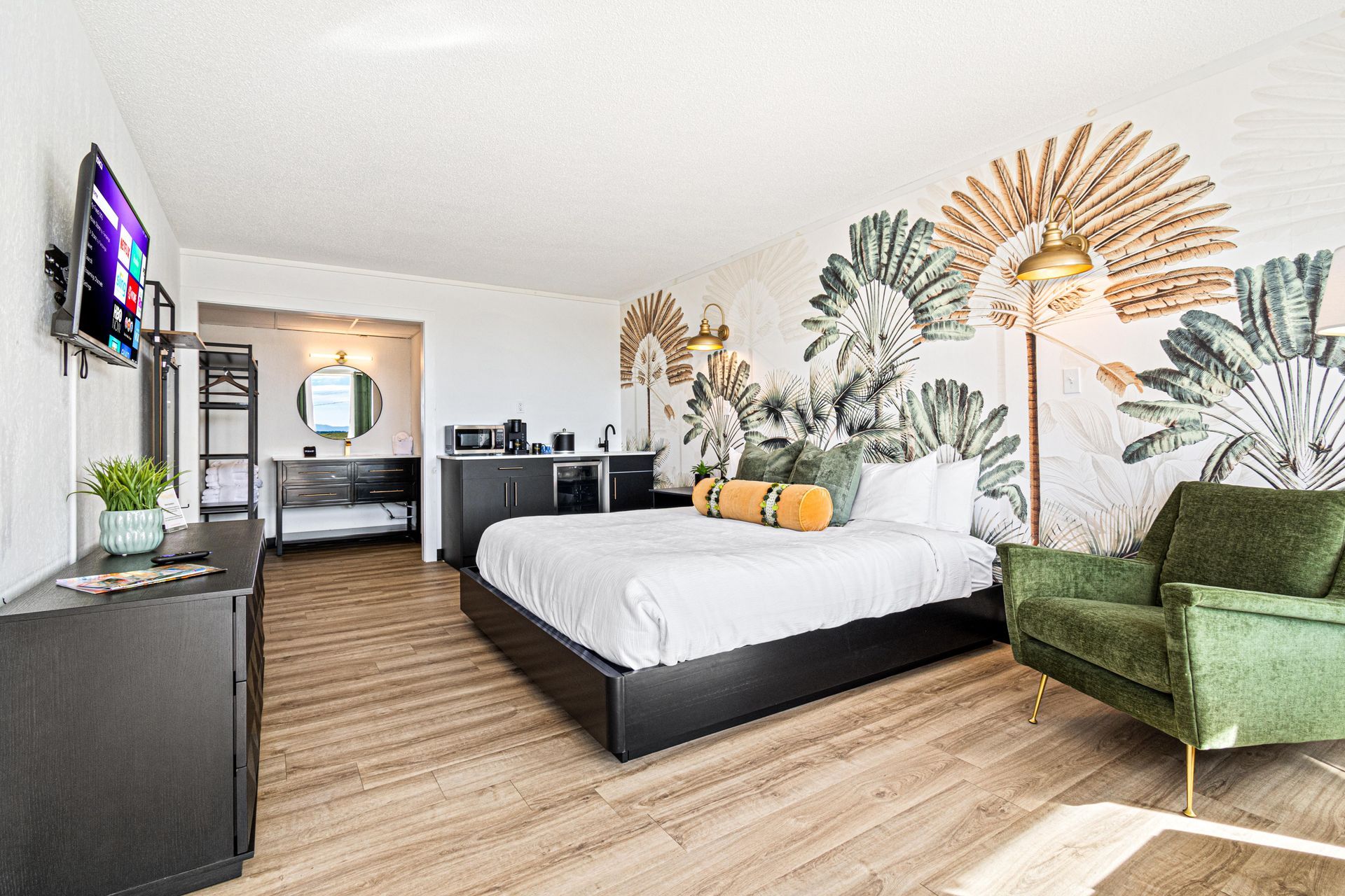 Hotel room with bed, green armchair, and tropical mural.