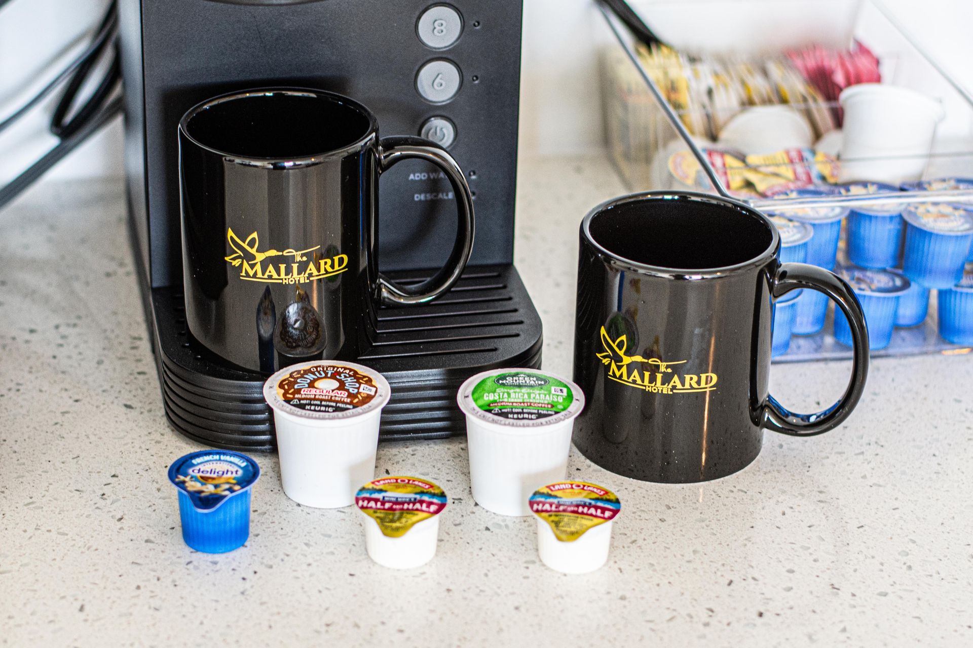 Coffee K-Cup machine with 2 coffee mugs and different kinds of creamer
