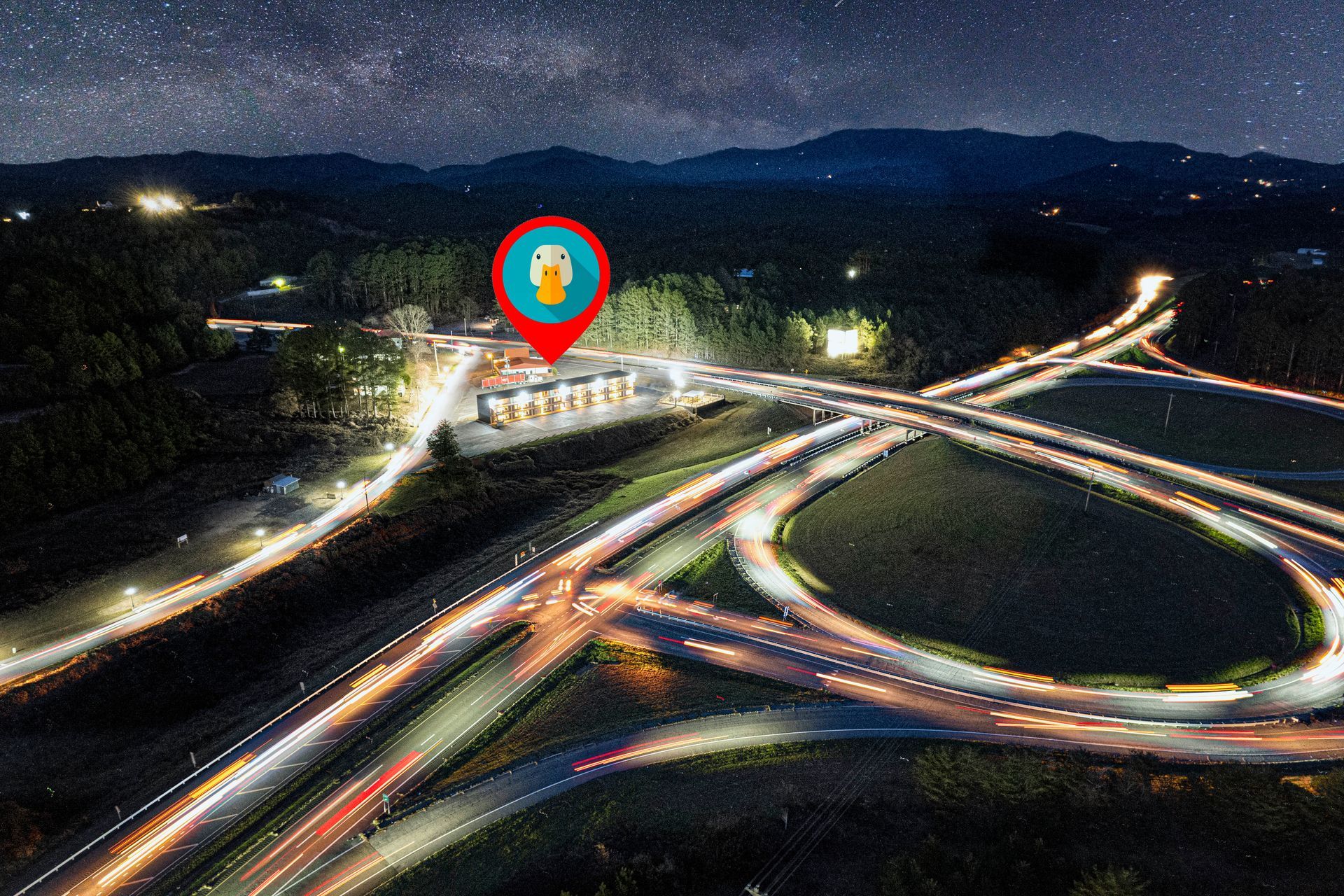 Night aerial view of highway interchange with a marked location pin.